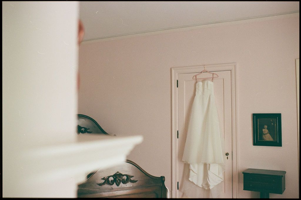 A white dress hanging on a door in a room with teal accents and soft lighting at Strong Mansion on Sugarloaf Mountain