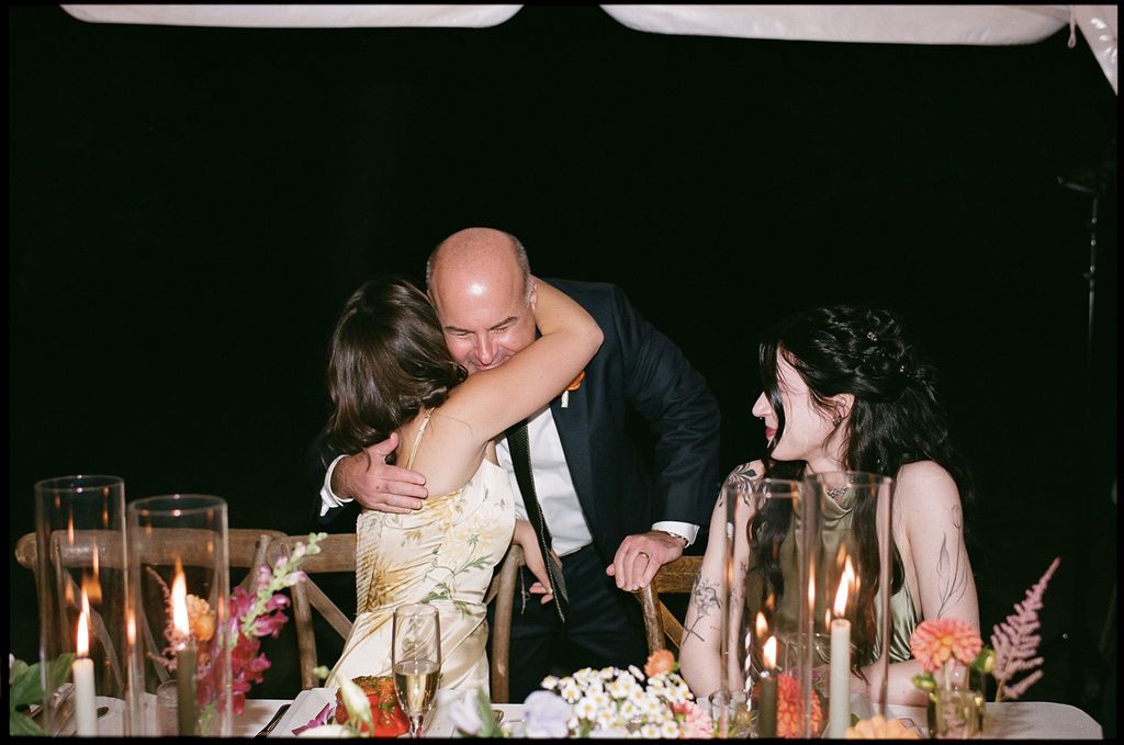 An intimate moment shared between guests at an elegantly decorated wedding reception dinner table.