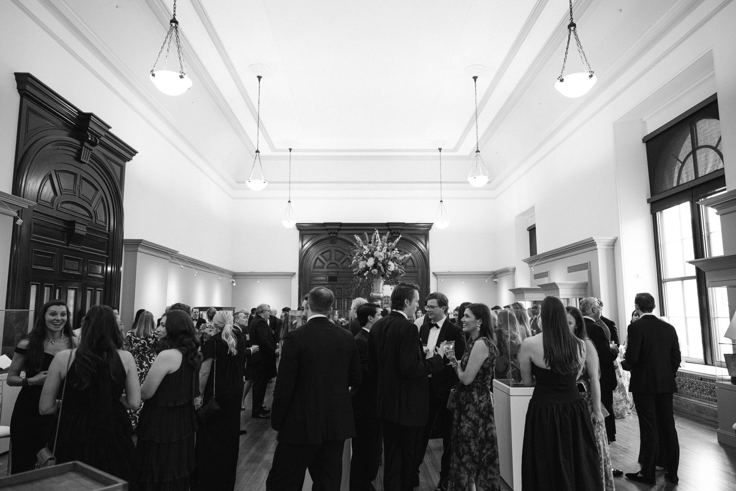 Wedding reception guests mingling in an elegant white interior space.