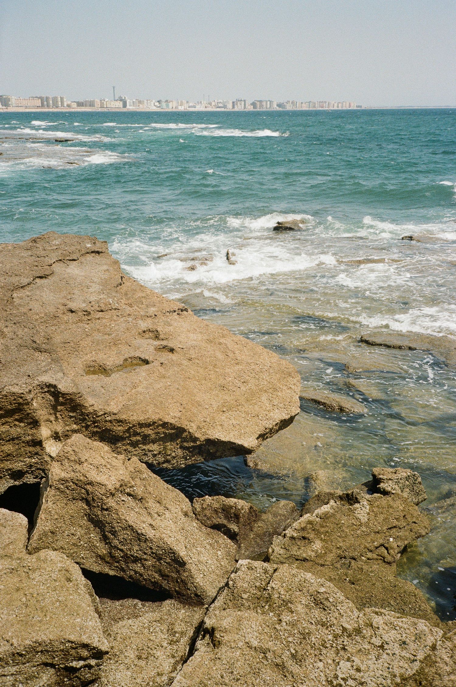 Rocky coastline with waves crashing against weathered limestone formations.