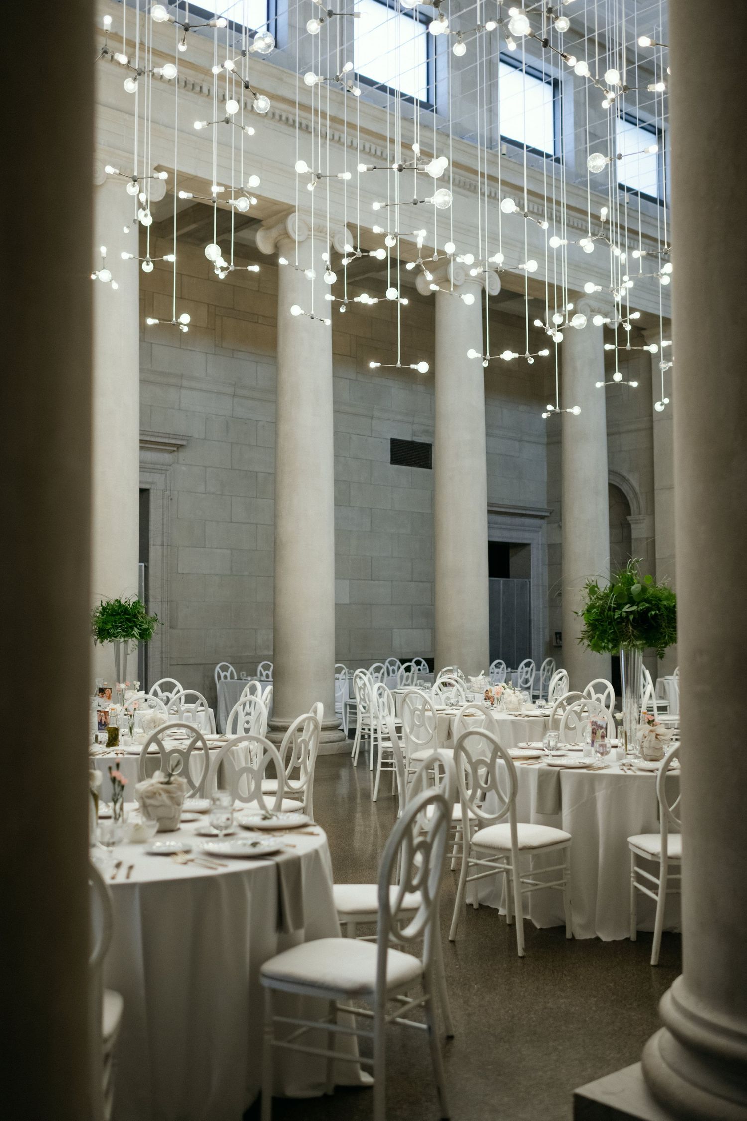 Elegant wedding reception hall with white tables and hanging lights creating a magical atmosphere.