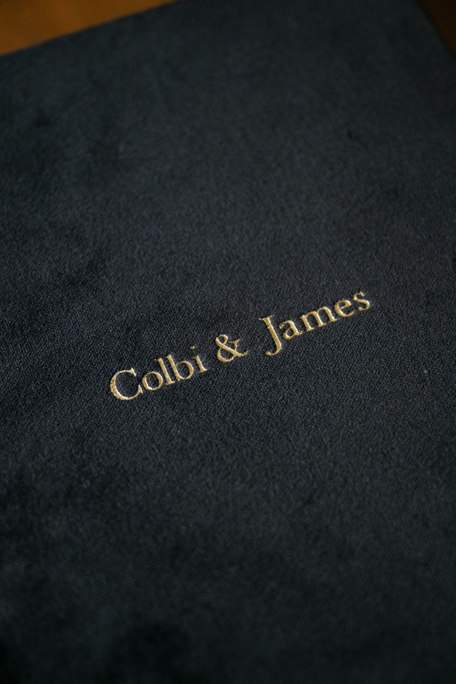 Gold text fragments appear on a dark textured background showing partial words in an elegant typeface.