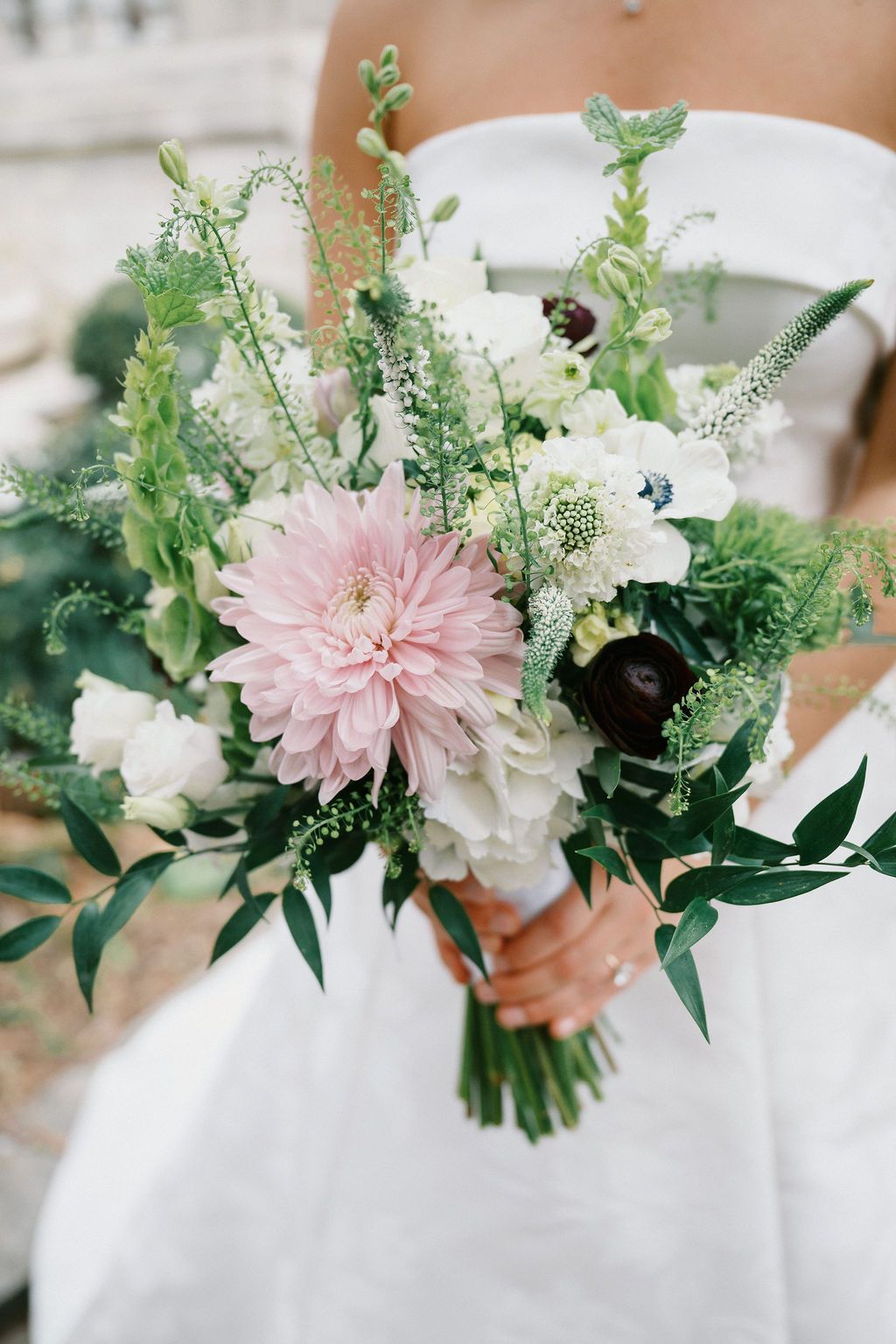 Romantic spring wedding bouquet with pink dahlia, white flowers and greenery.