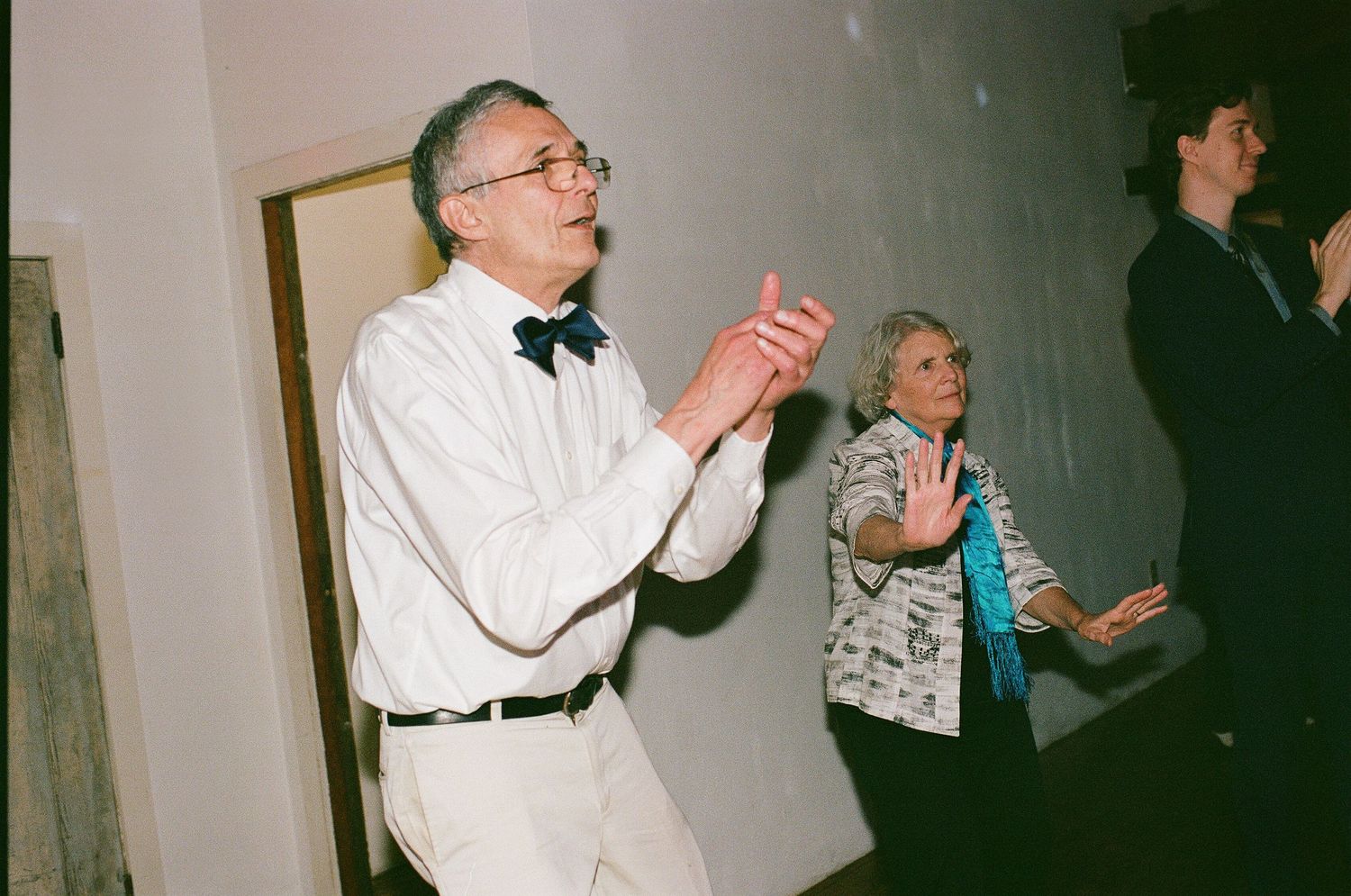 People dancing and clapping at an indoor celebration event.