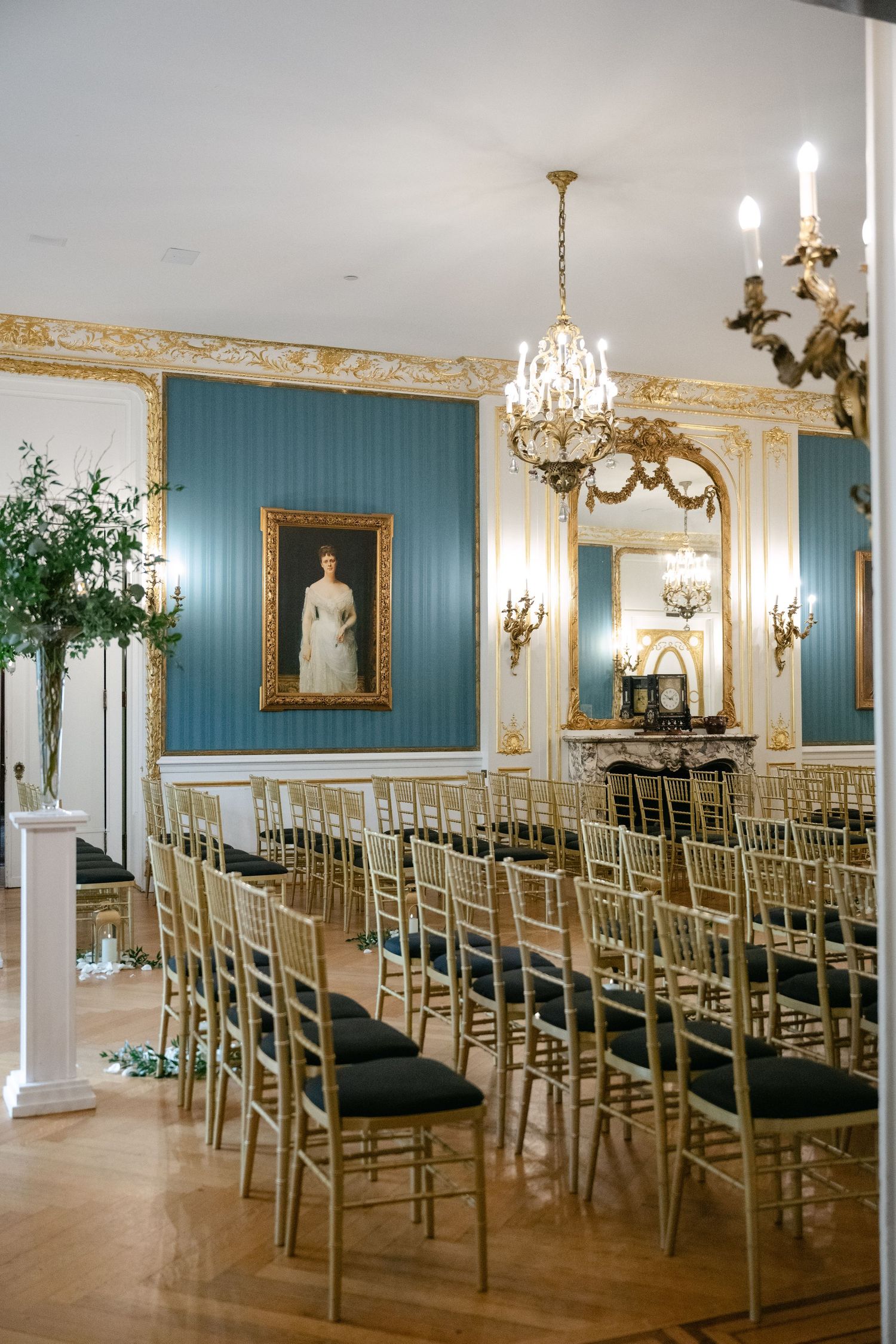 Elegant ballroom with blue walls, crystal chandeliers, and gold chiavari chairs set up for a ceremony at a Baltimore engineers club wedding