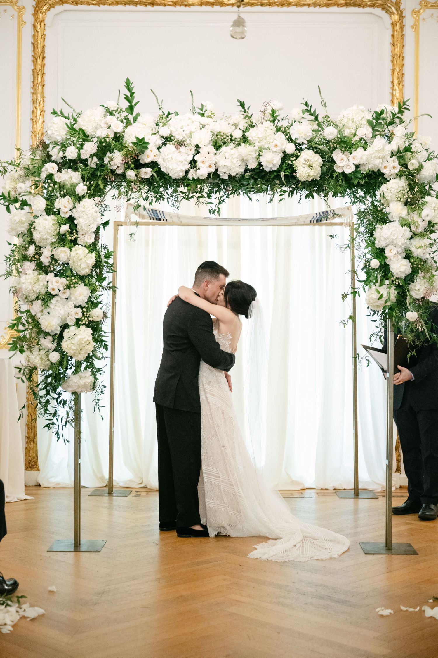 Elegant wedding ceremony space with white floral arch and gold accents in a bright reception hall at a Baltimore engineers club wedding