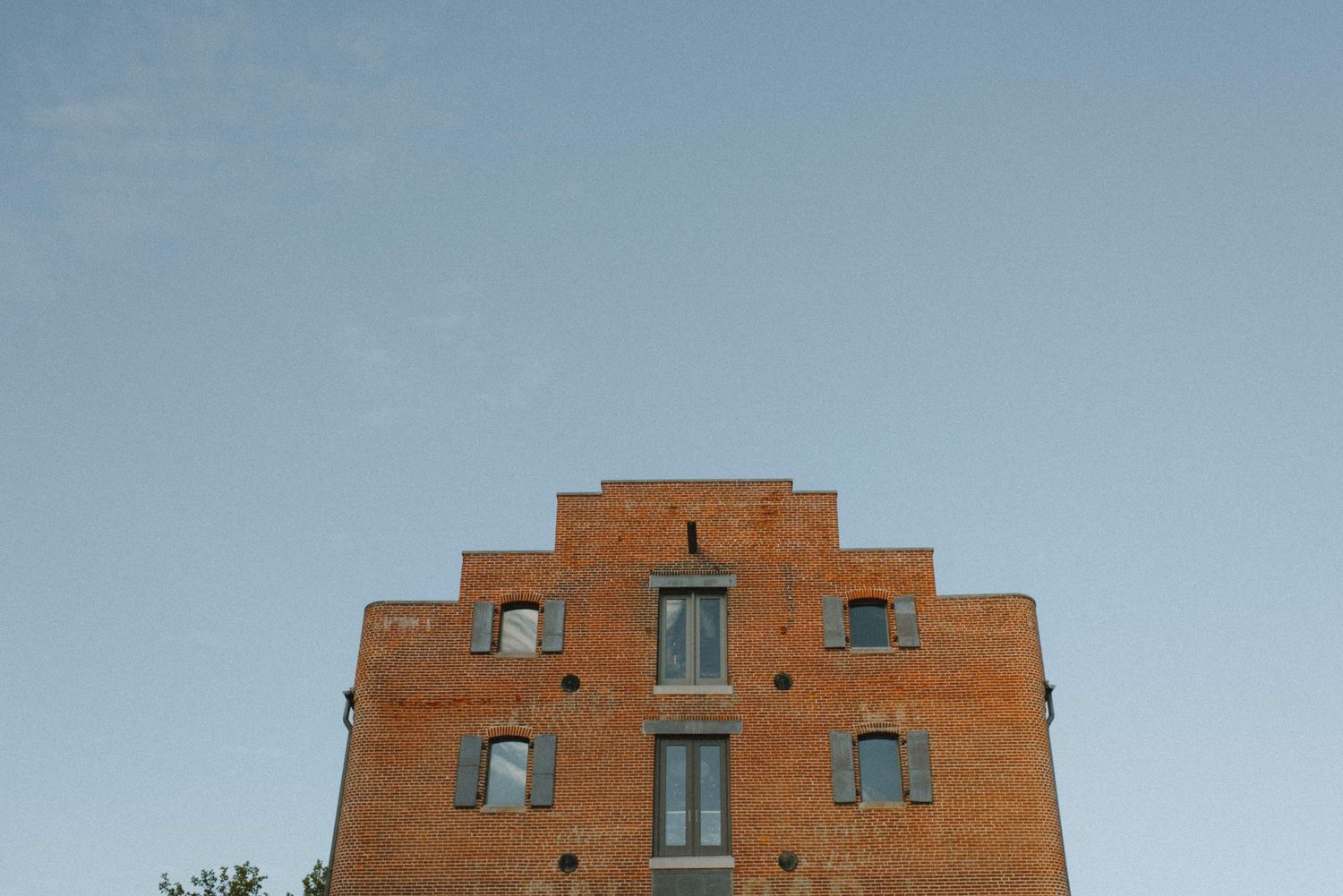 Historic brick building with stepped gable facade against blue sky.
