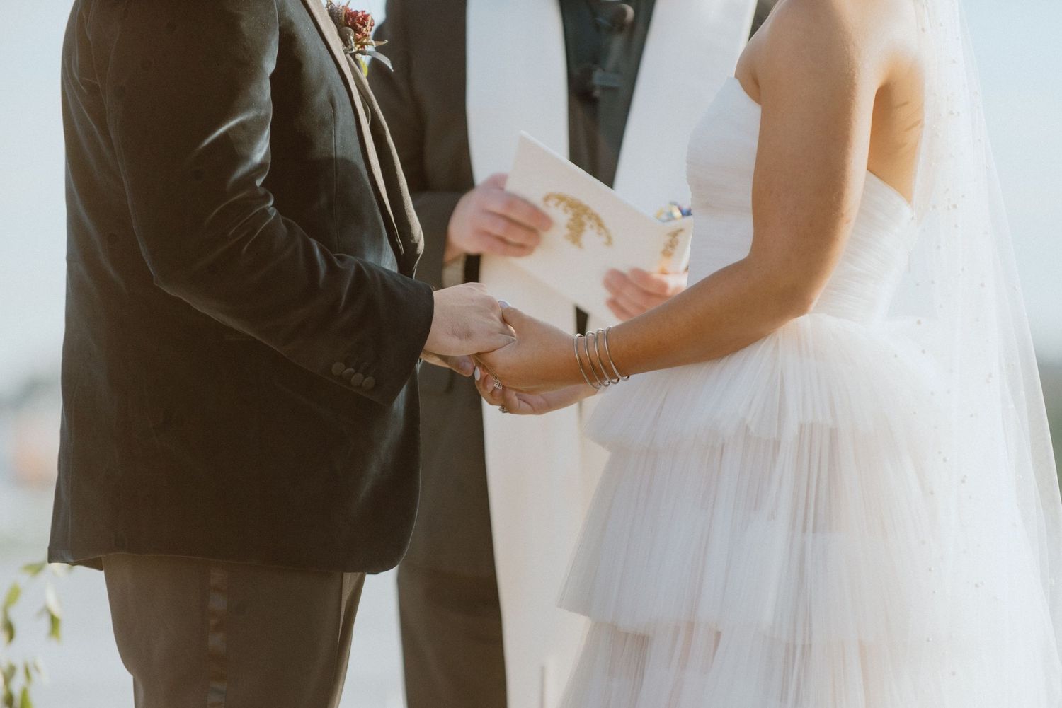 Close-up shot of a couple exchanging vows during their wedding ceremony on a sunny day.