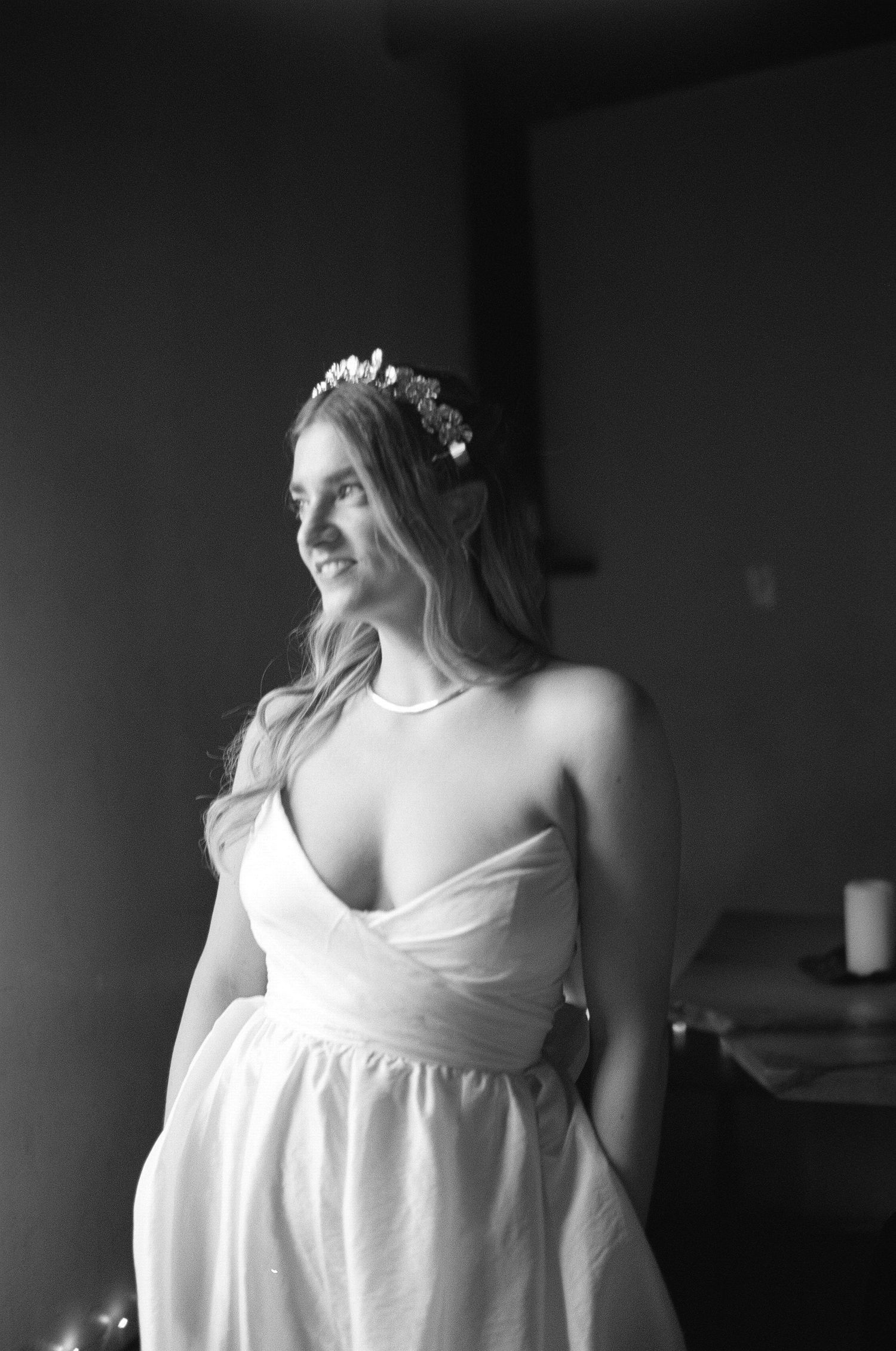Black and white portrait of a bride in a flowing white dress with delicate floral crown looking to the side at Fadensonnen in Baltimore