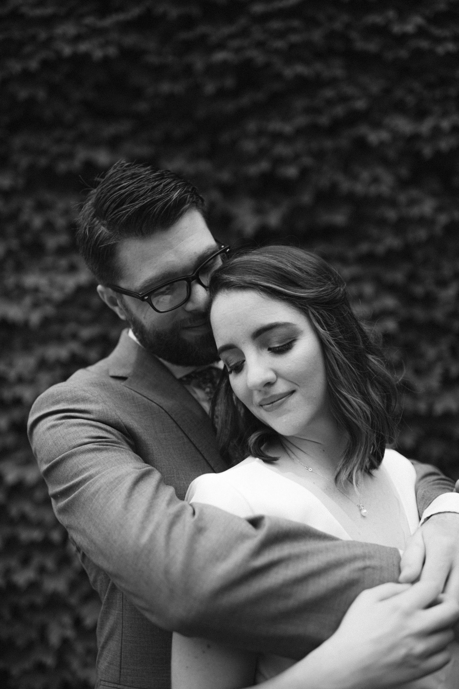 Dramatic wedding portrait with couple standing against massive ivy-covered wall.