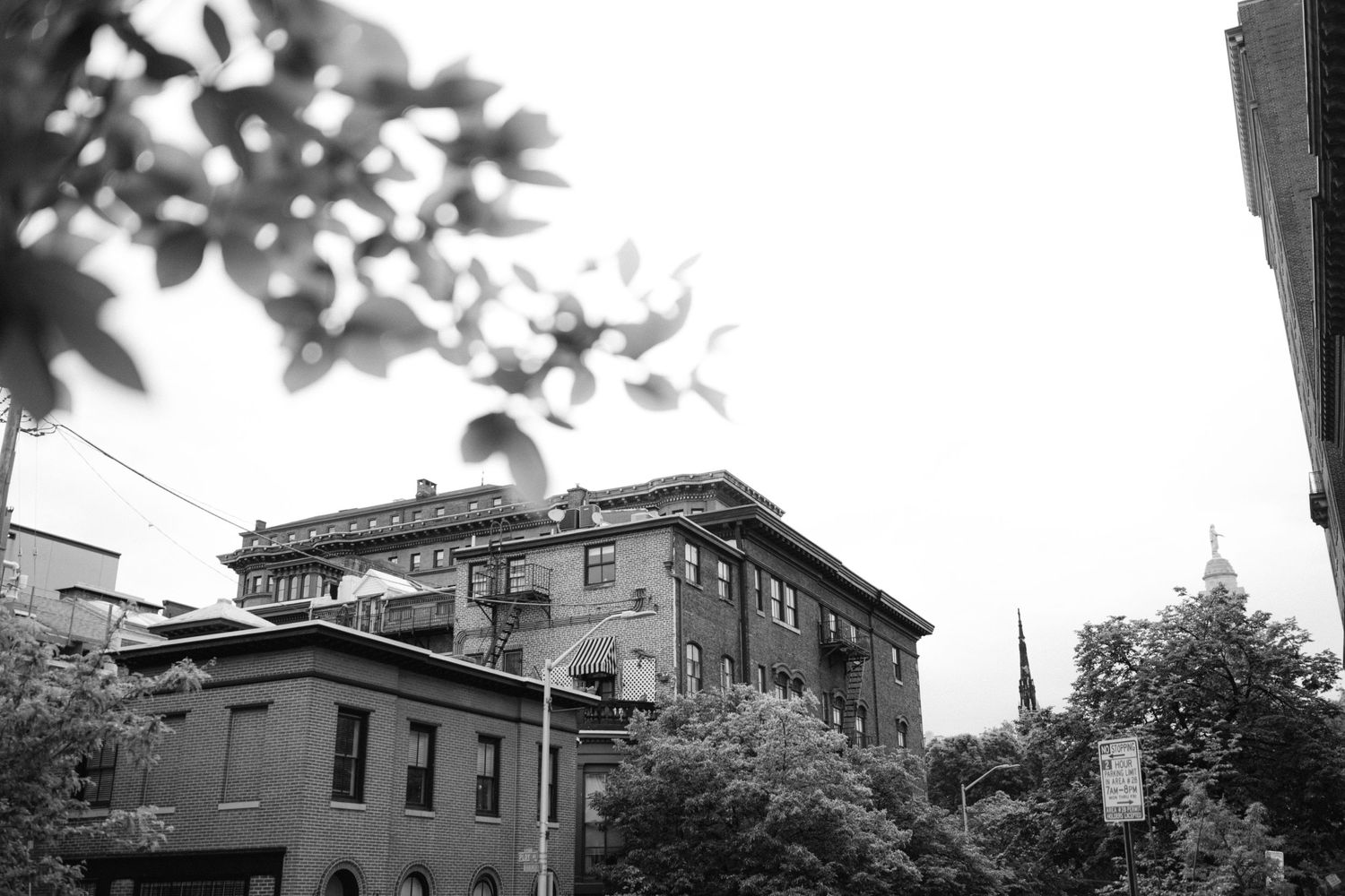 Historic brick buildings with architectural details shown in black and white against a cloudy sky.