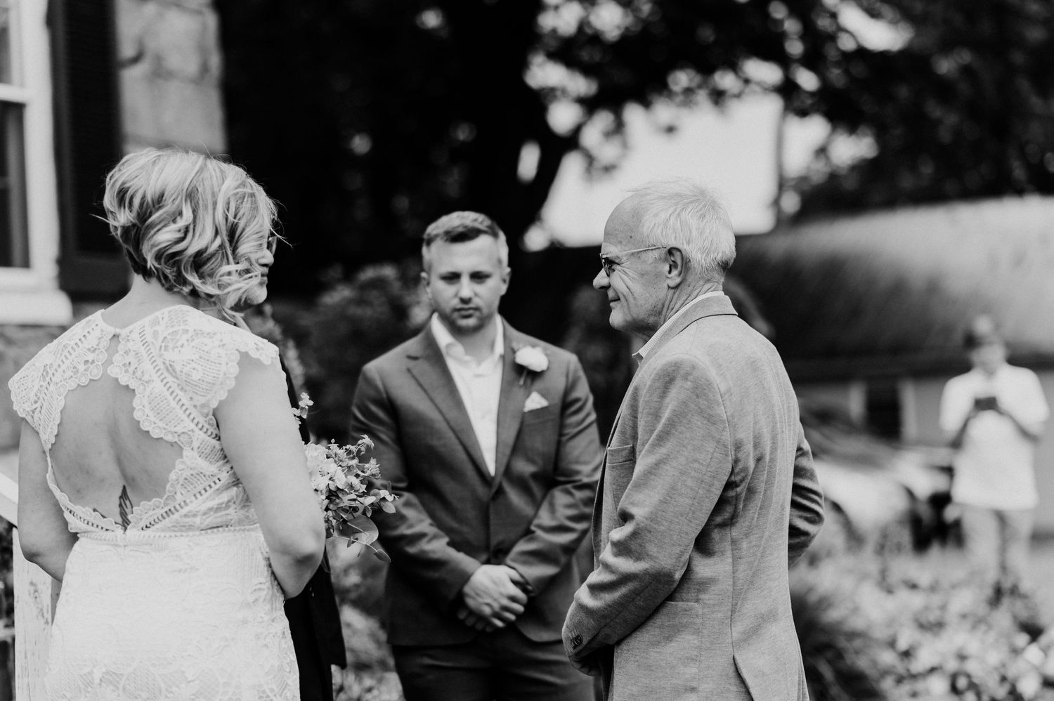 Black and white photo of intimate outdoor gathering at stone house entrance.