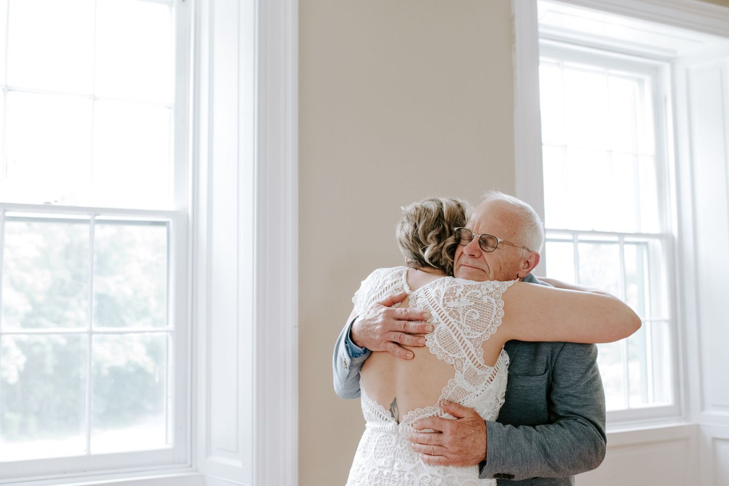 An emotional moment captured as two people share an embrace near bright windows.