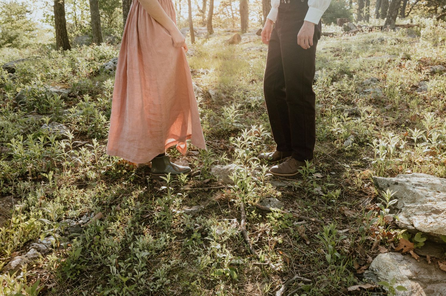 Two people in contrasting outfits standing in wildflowers during sunset.