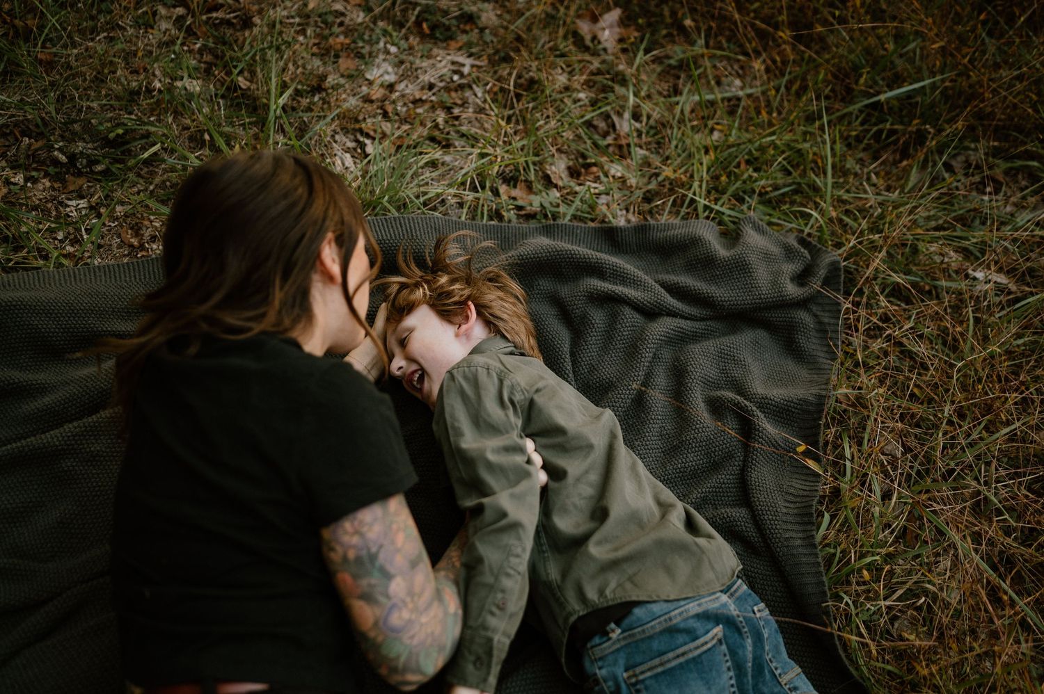 An intimate black and white photograph of two people sharing a tender moment on a blanket outdoors.
