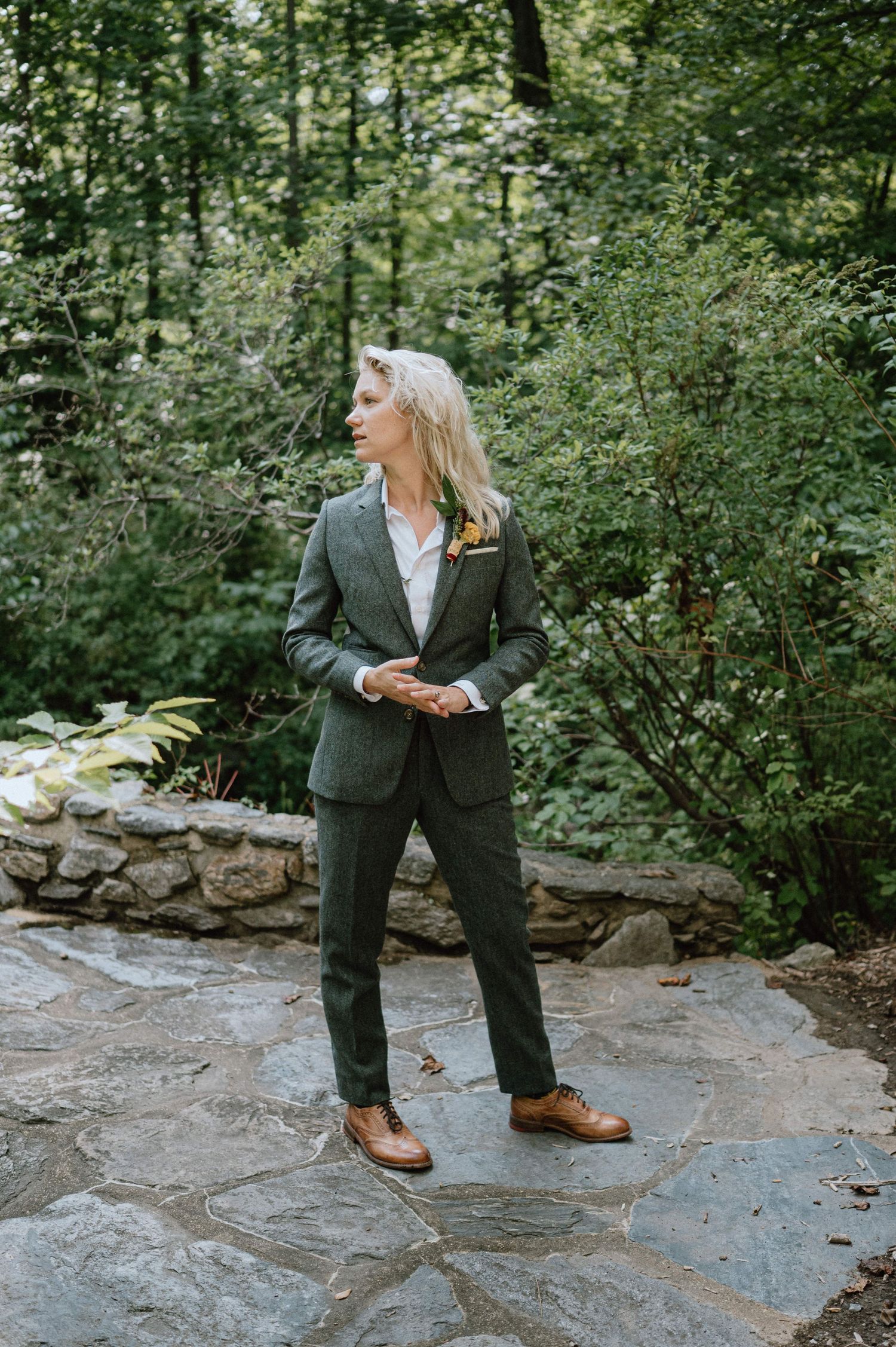 Person in a green suit stands on stone pathway surrounded by forest greenery.