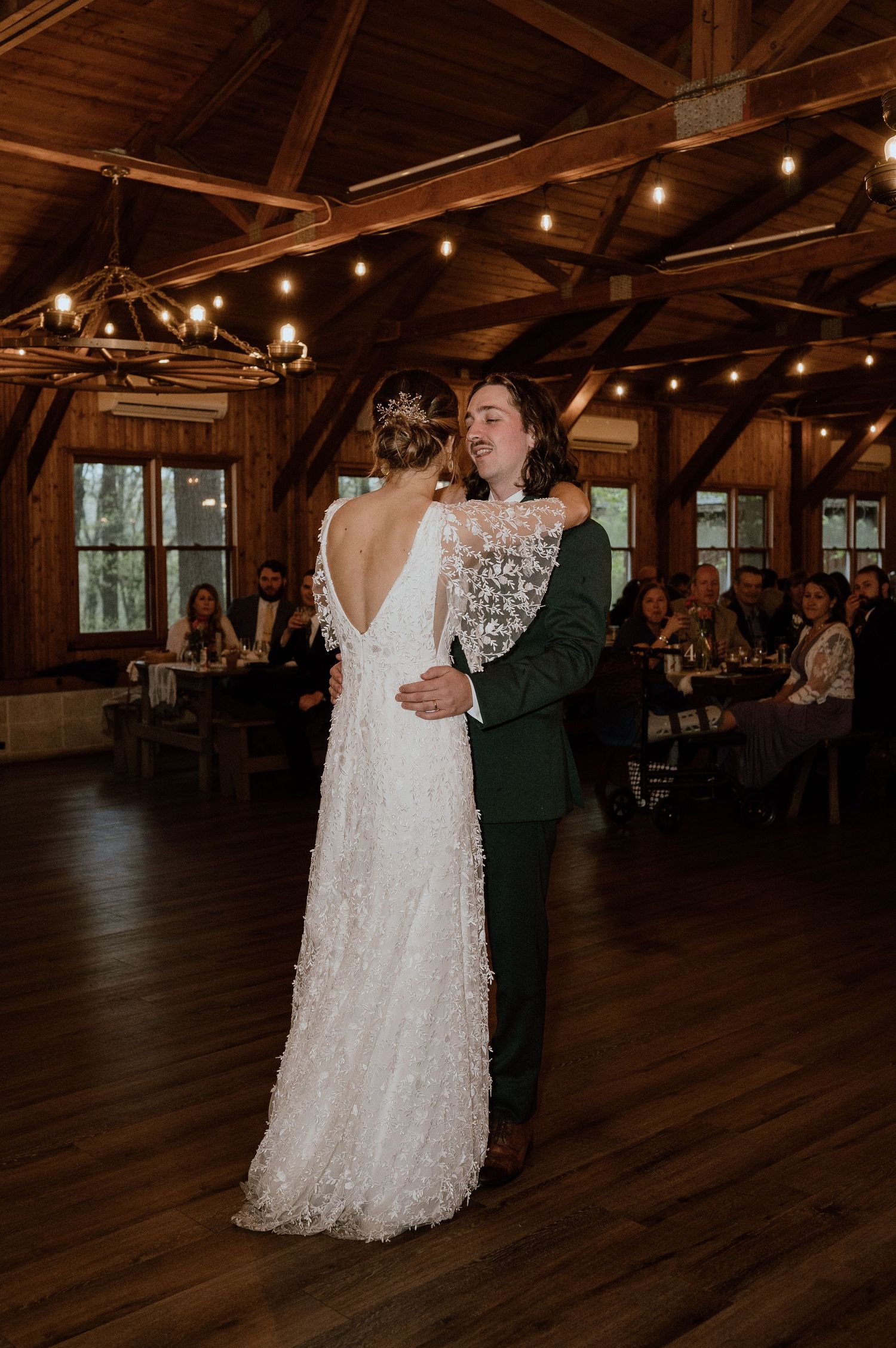 A couple shares their first dance in a rustic barn venue with string lights.