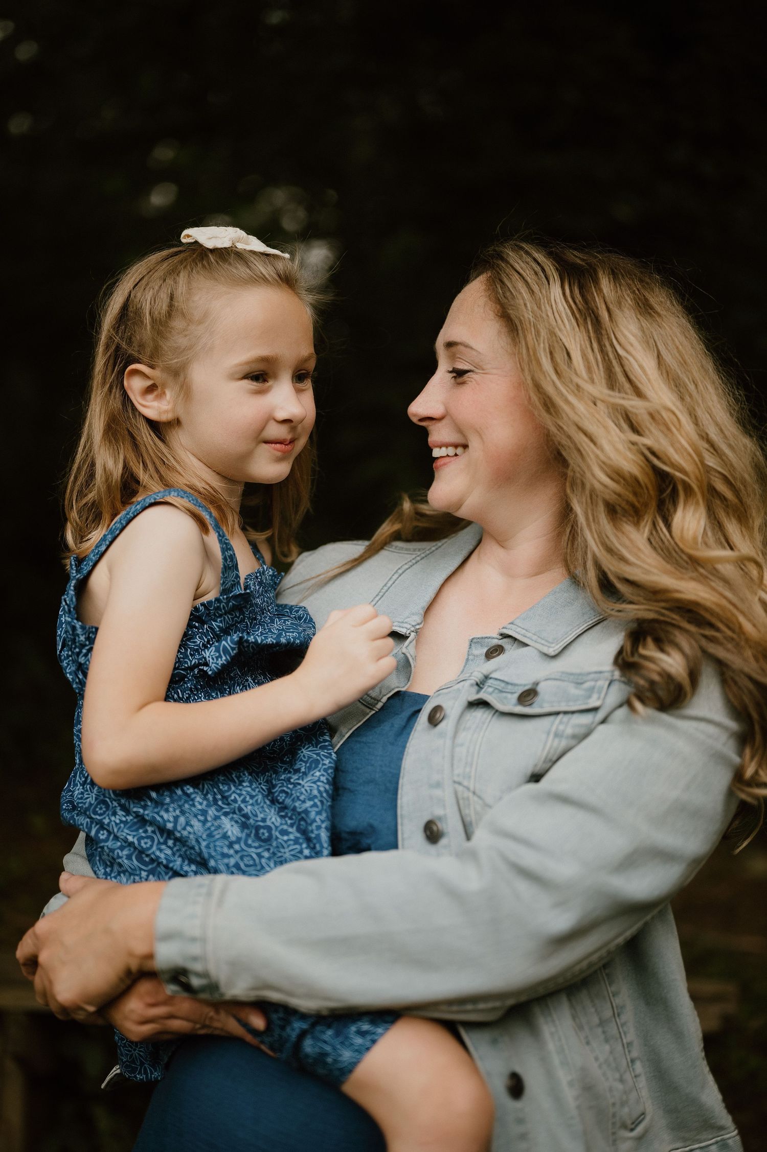 Sweet outdoor portrait of parent and child embracing while wearing denim jackets.