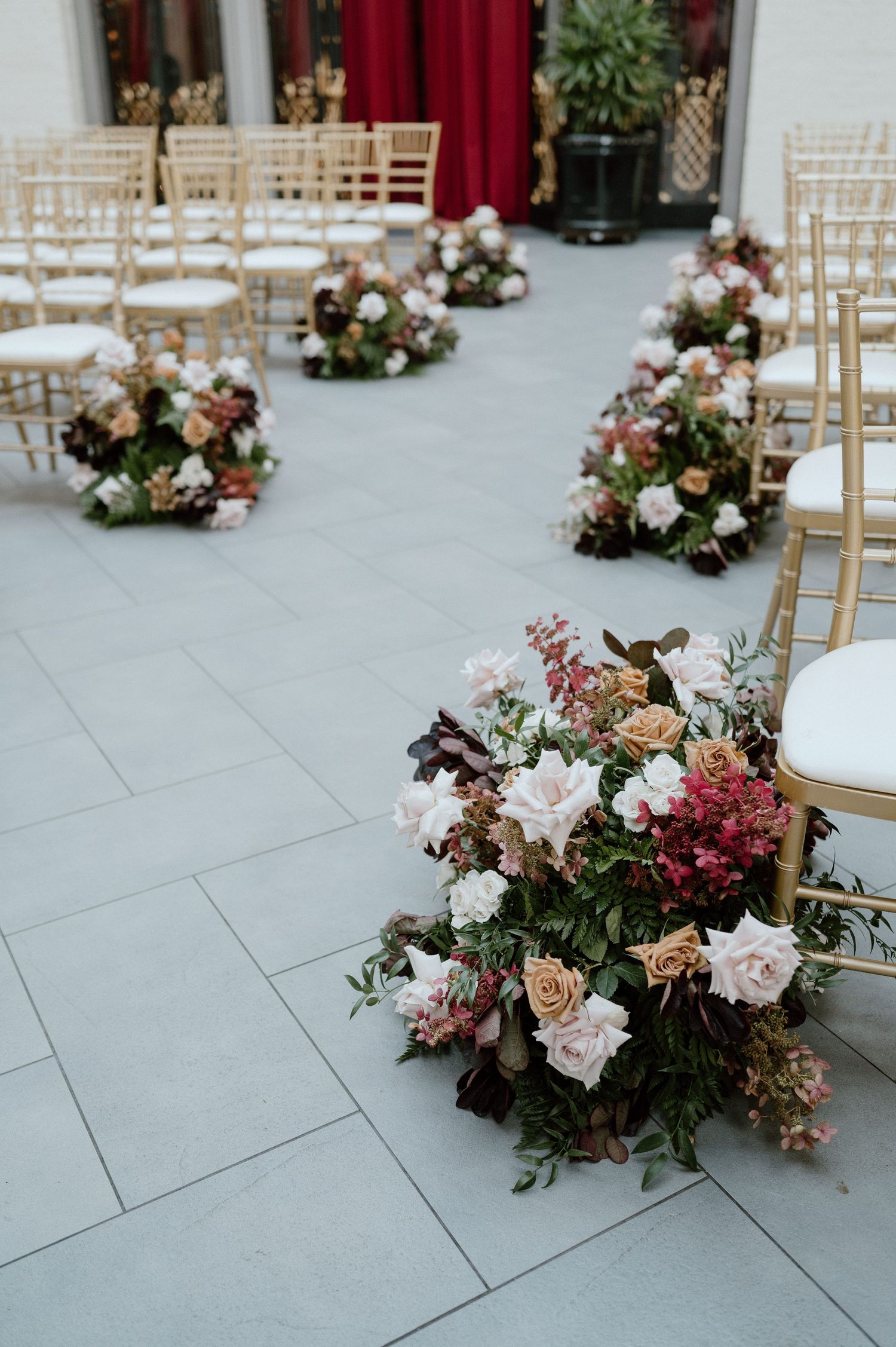 Close-up of romantic pink and white floral arrangements lining ceremony aisle.