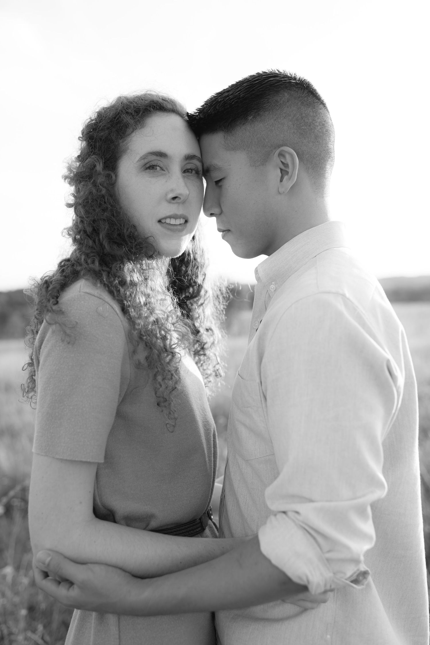Black and white portrait of couple in intimate embrace outdoors.