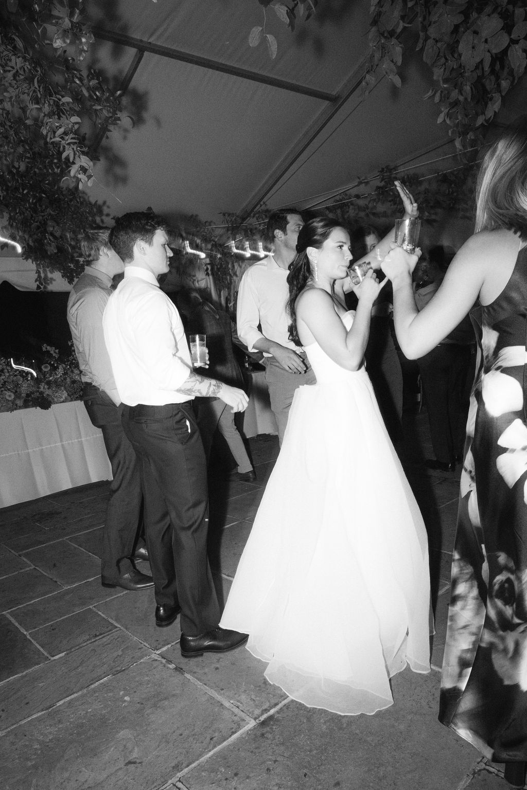Wedding guests dance together at an elegant reception with a bride in a white ballgown on the dance floor.