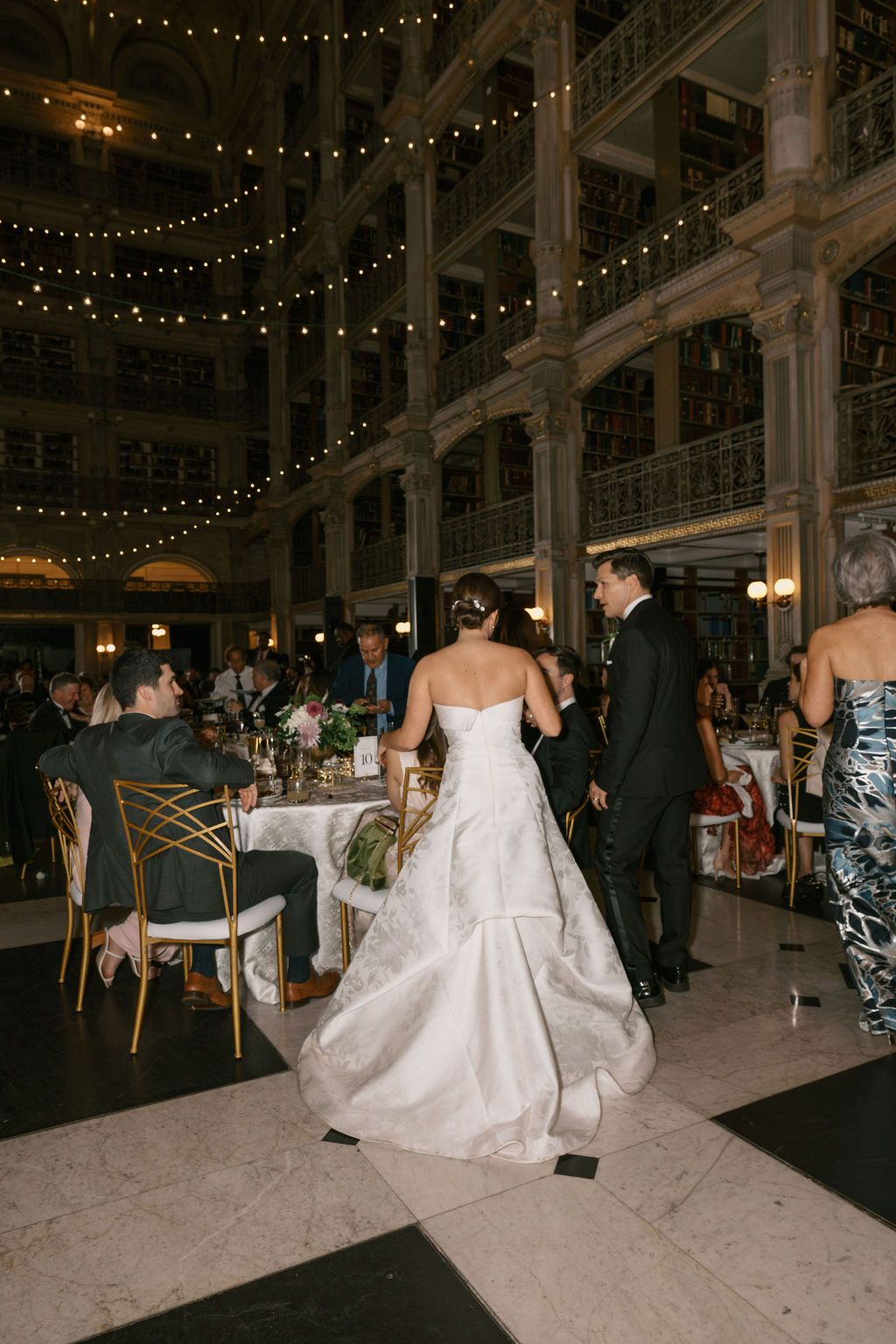 Wedding reception in a grand ballroom with string lights and guests mingling at George Peabody Library Wedding in Baltimore