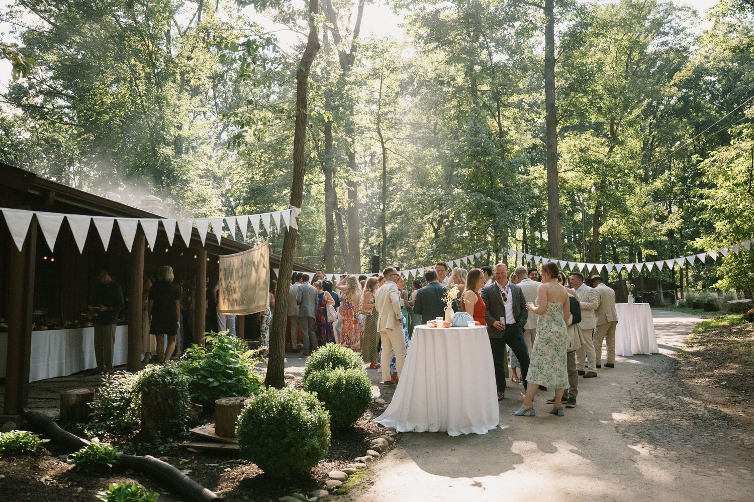 Outdoor wedding venue with white bunting decorations strung between trees.