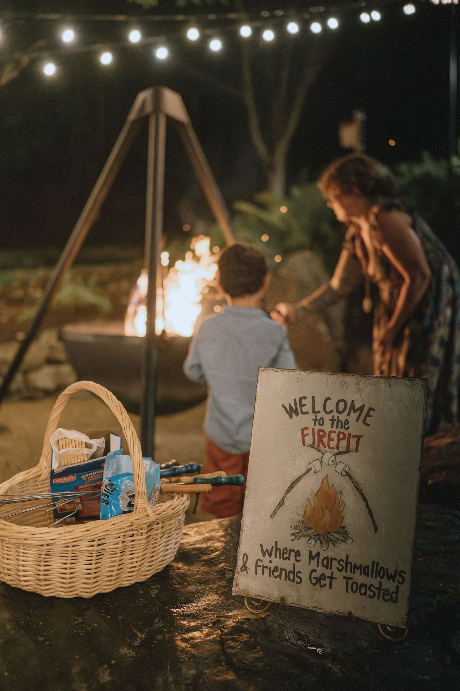 S'mores station at night with a fire pit and welcome sign for marshmallow roasting.