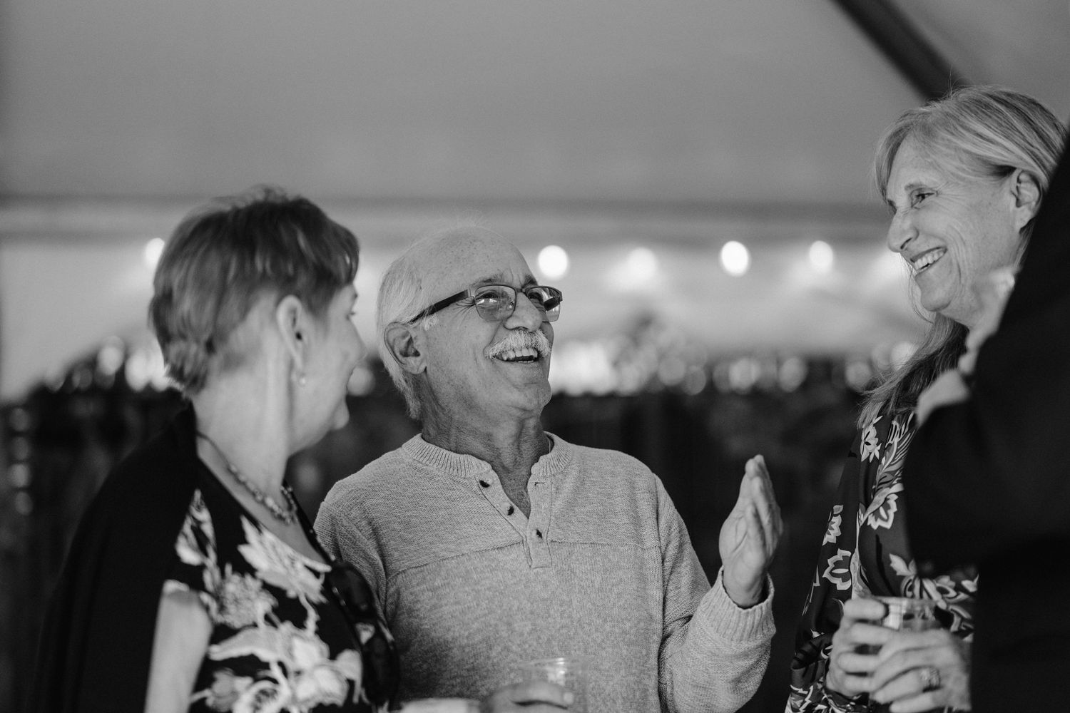 Three people engaged in lively conversation at an evening gathering.