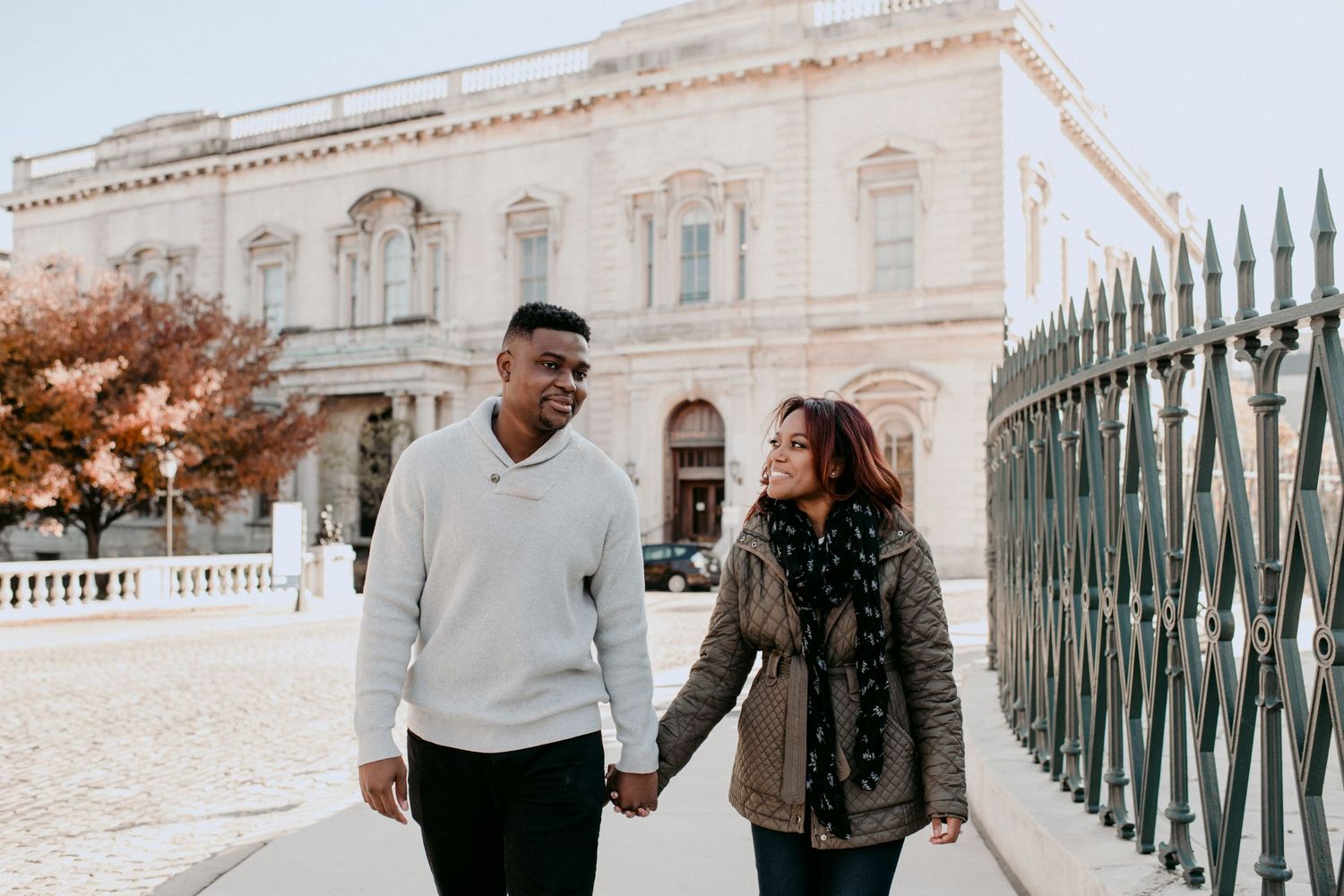 A couple sharing a happy moment while walking near a classical building.