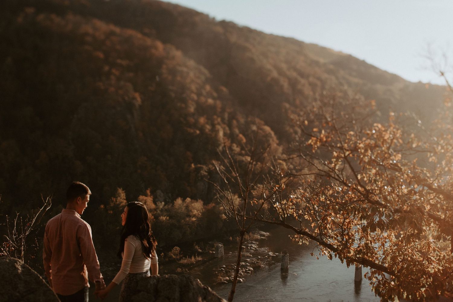 A couple enjoying sunset views over mountainous terrain and river valley.
