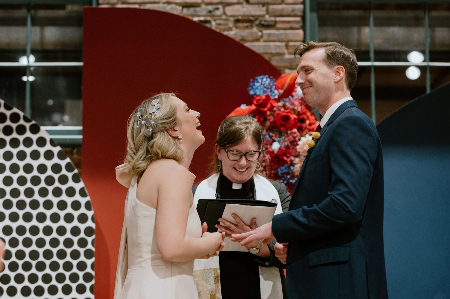 Wedding ceremony with a modern geometric backdrop featuring red floral arrangements.