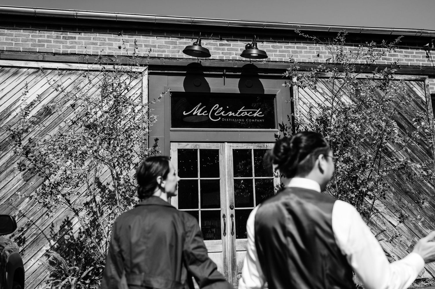 A black and white exterior shot of a distillery entrance with vintage signage.