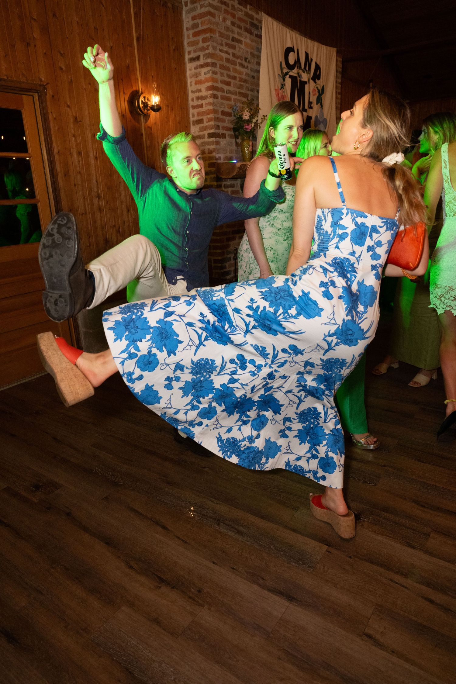 Dancers in a rustic venue showing energetic moves with green lighting effects on a wooden floor.