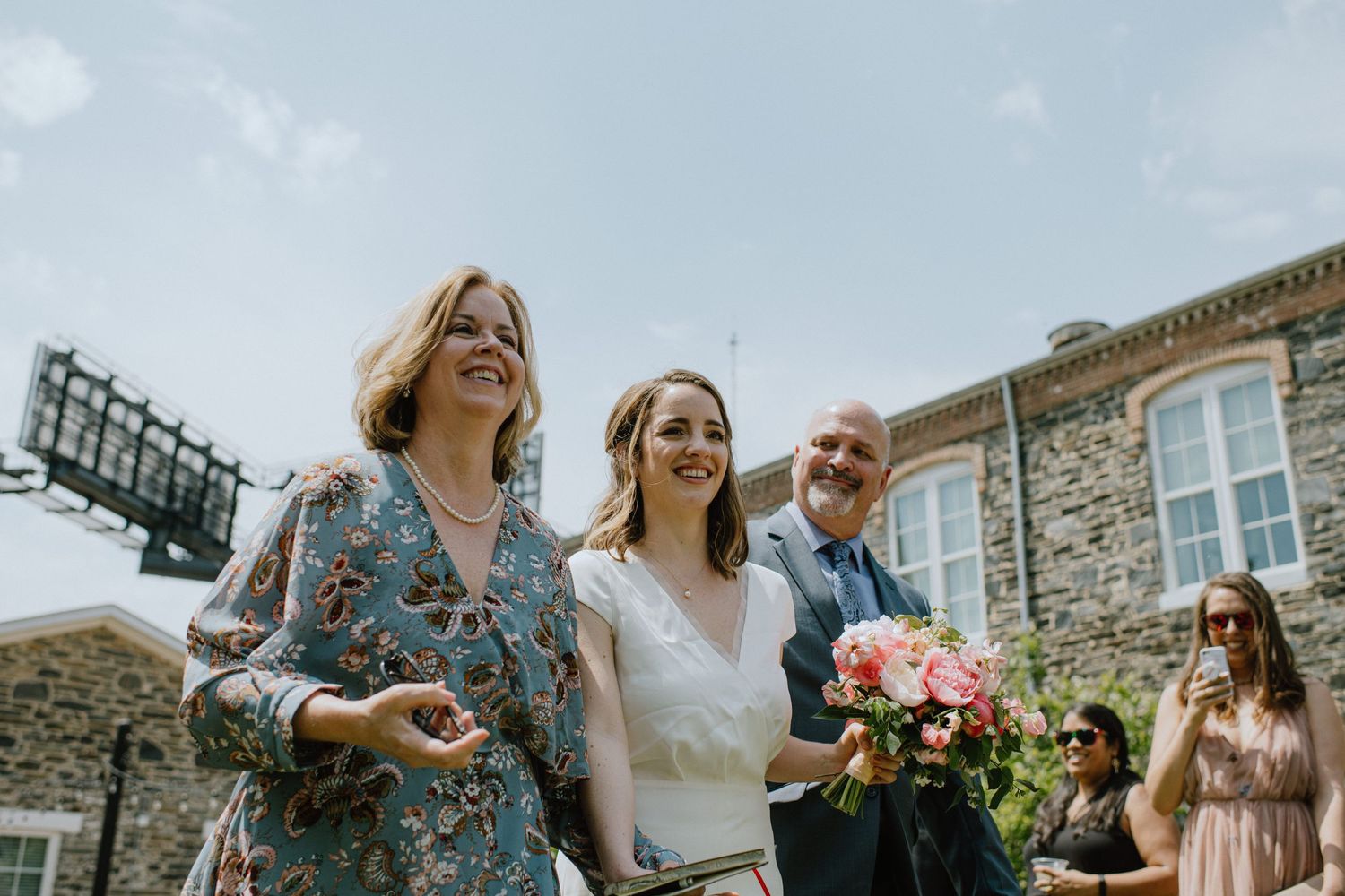 Candid outdoor wedding moment against stone building backdrop.