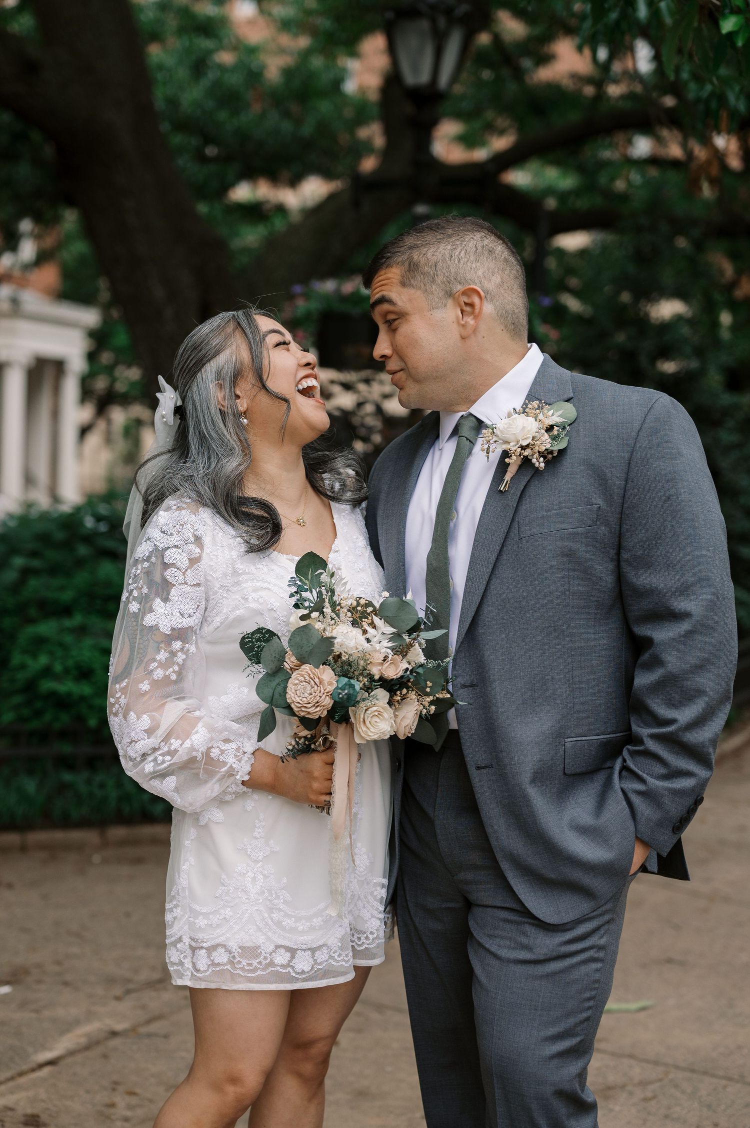 A couple shares a joyful moment together during their wedding photoshoot in a garden setting.