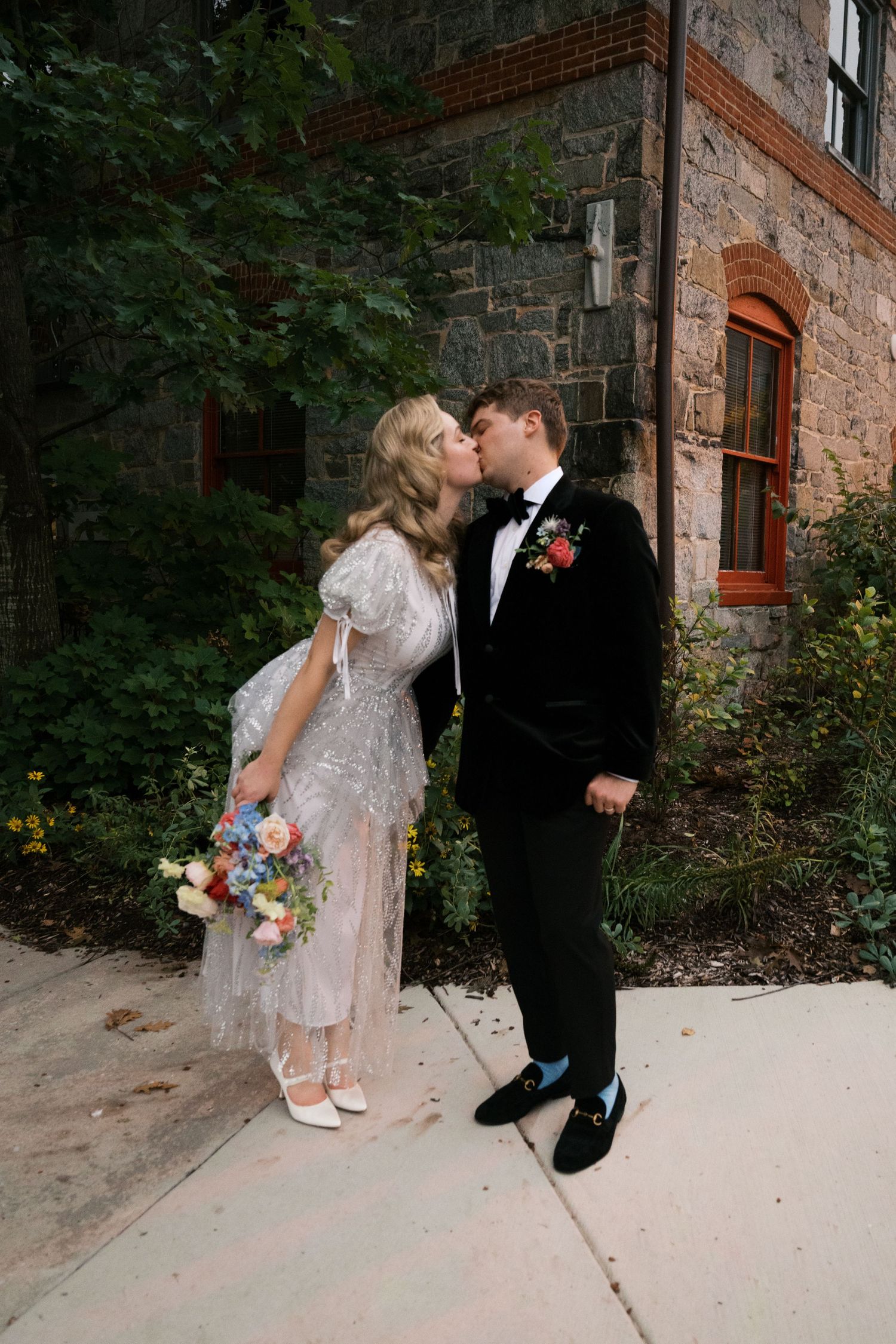 A couple shares a romantic moment outside a stone building on their wedding day.