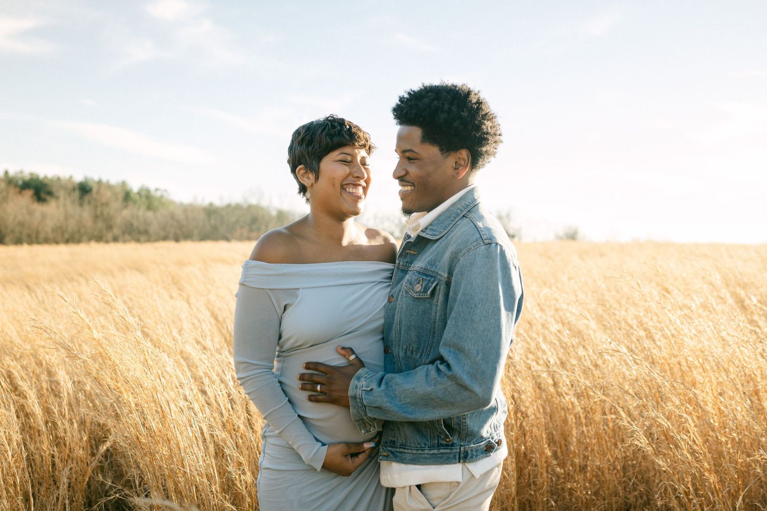 pregnant couple laughs together in field in maryland