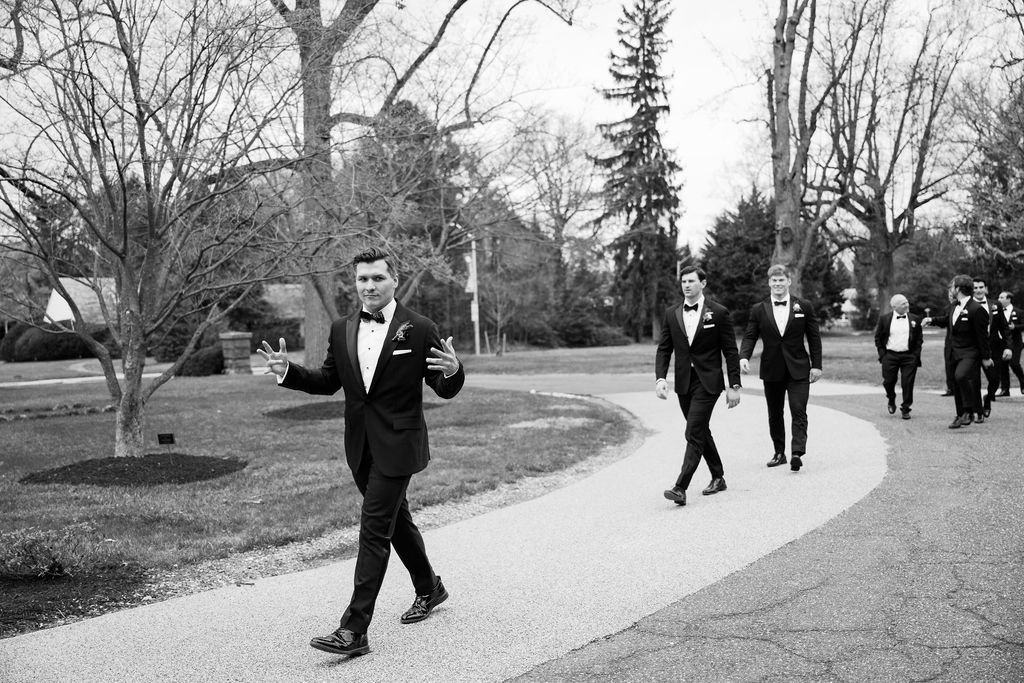 Wedding party walking along a tree-lined path in formal attire during winter.