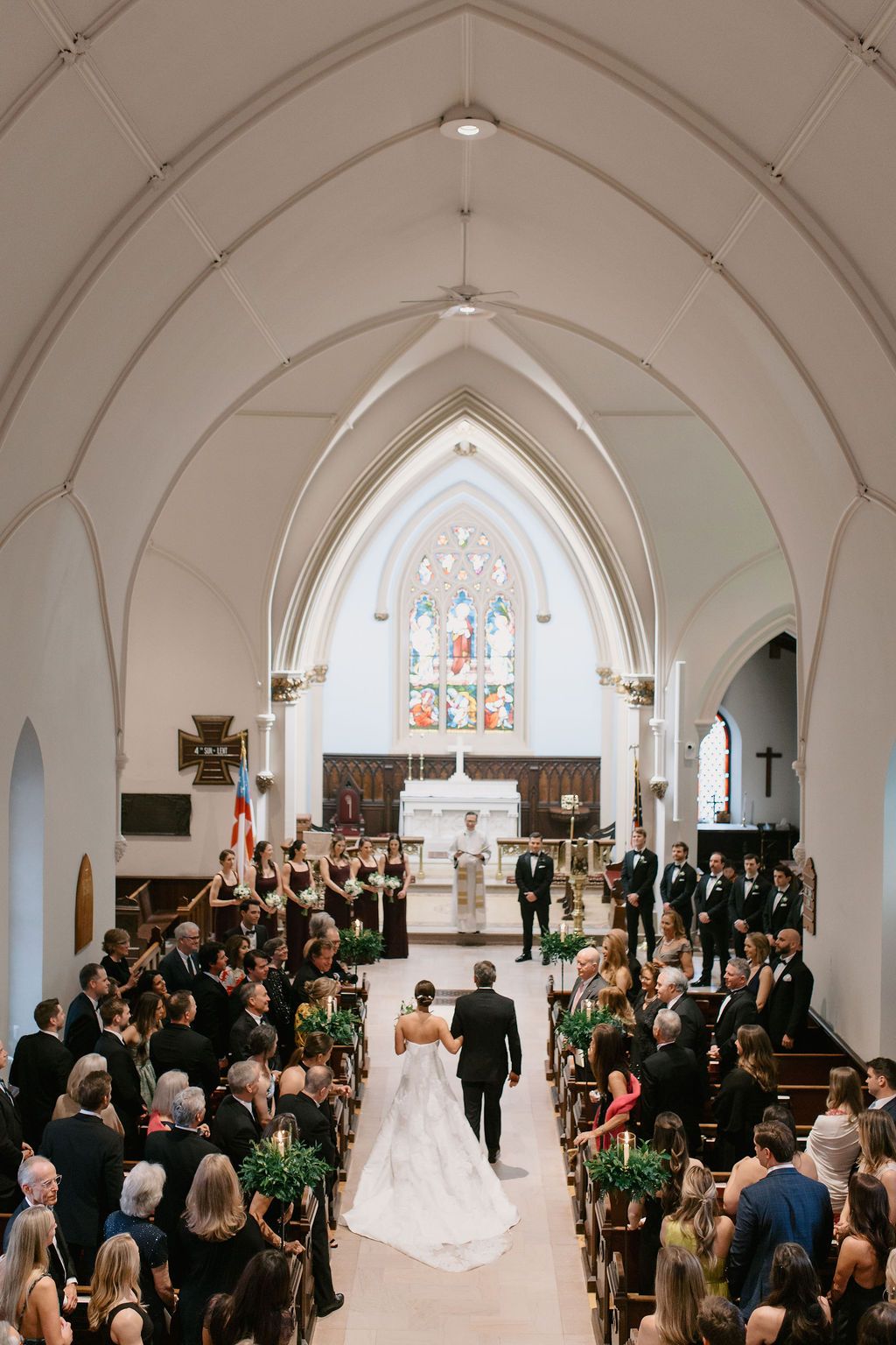 Wide angle view of a church wedding ceremony with guests filling the pews and vaulted ceiling above.
