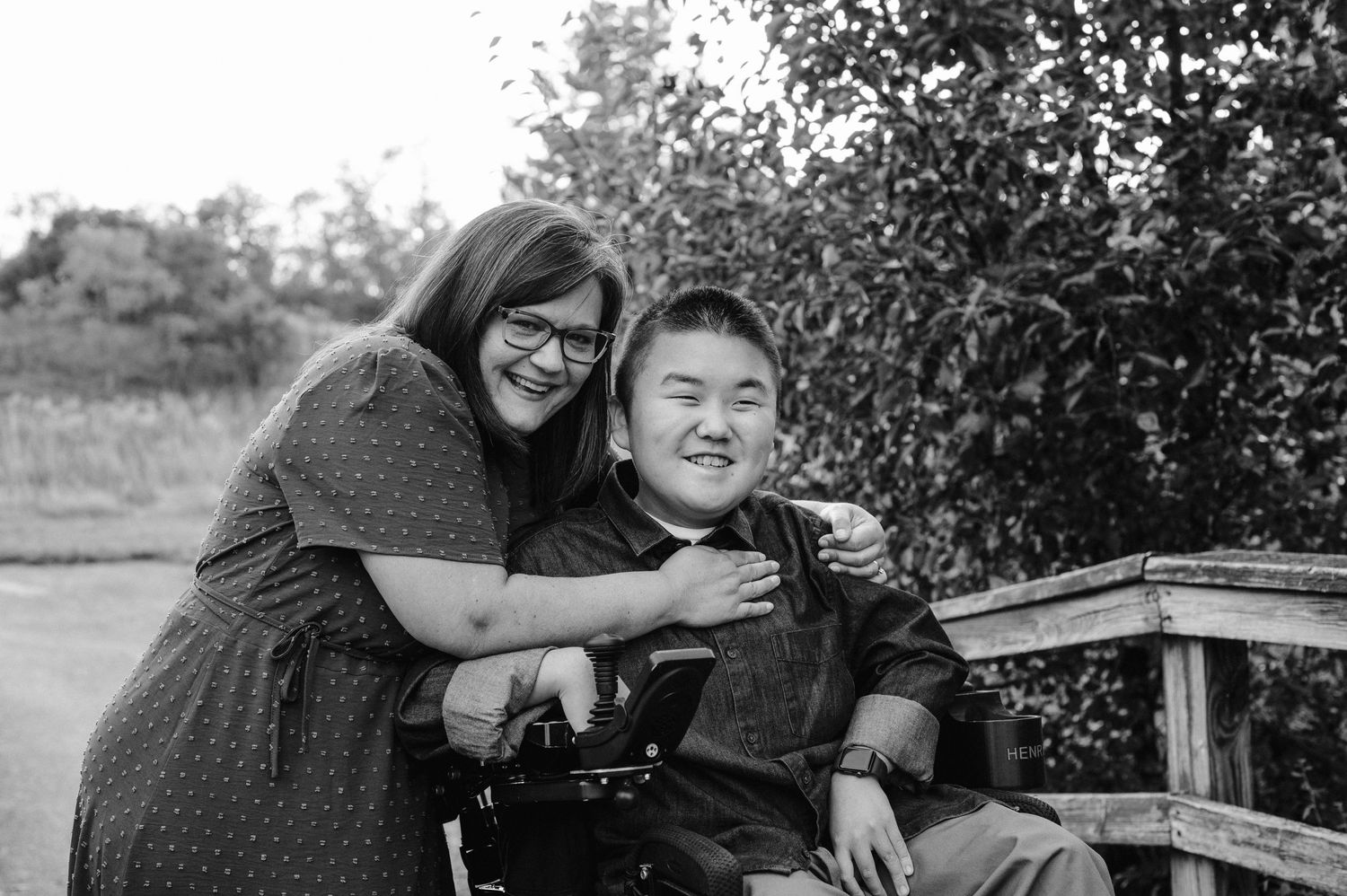A heartwarming black and white portrait of two people sharing a tender moment on a bench outdoors.