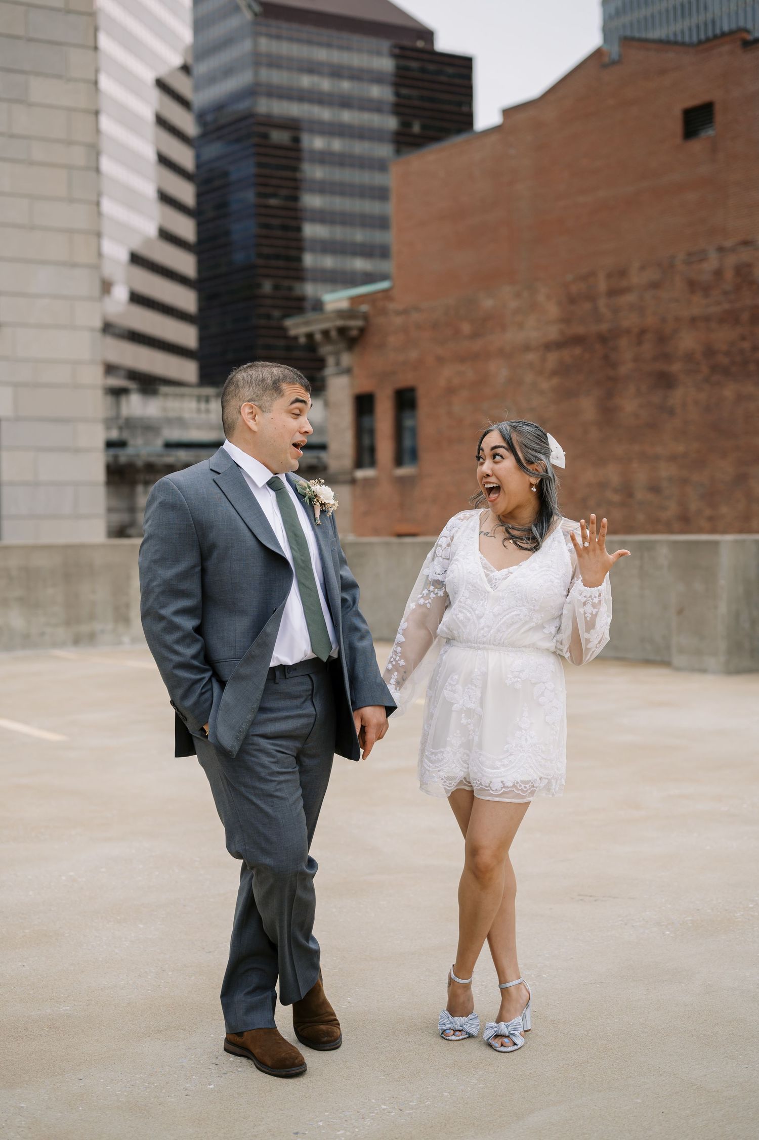 A couple in wedding attire shares a candid moment against an urban backdrop of tall buildings in baltimore.