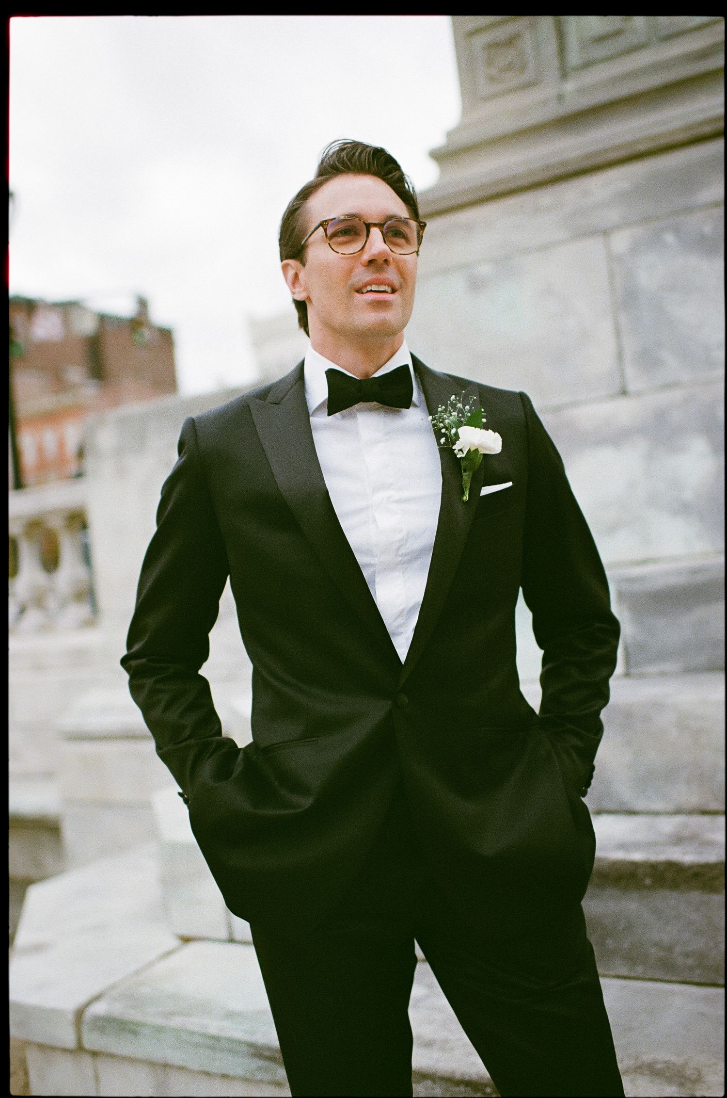 Classic black tuxedo with bowtie and boutonniere photographed on stone steps.