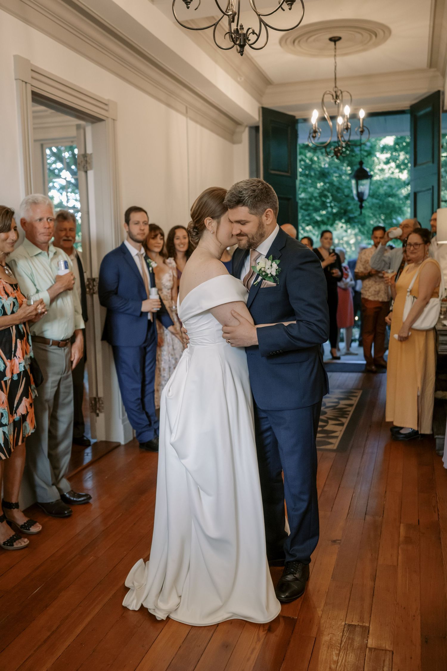 First dance moment at an elegant indoor wedding reception with hardwood floors and chandelier.