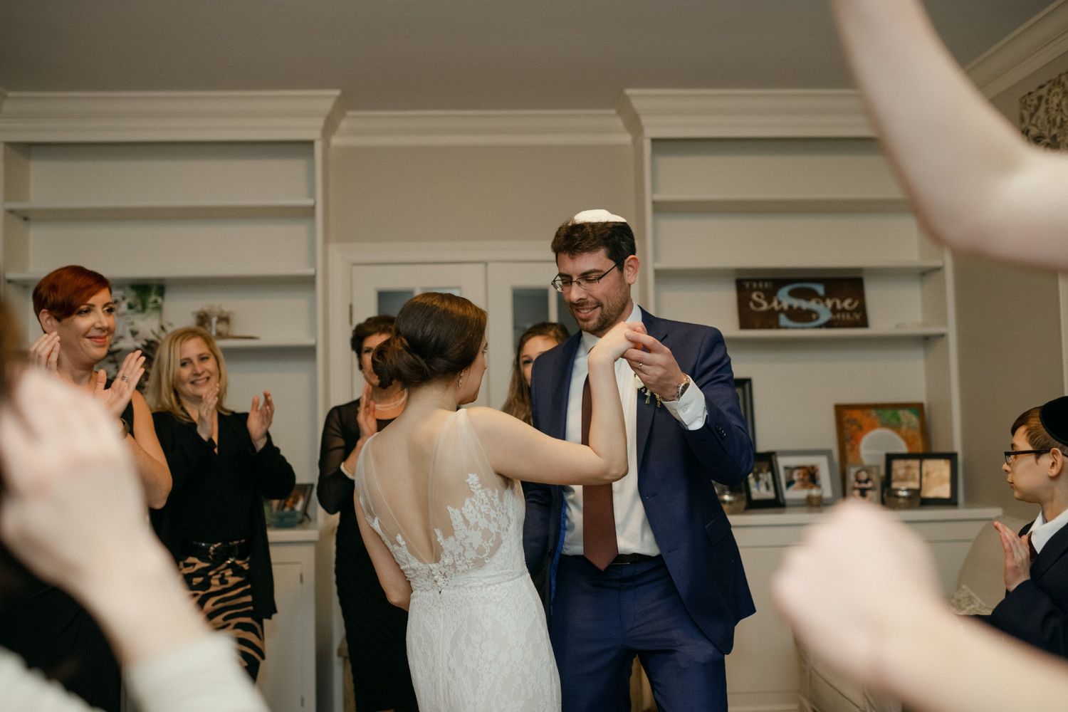 Wedding celebration showing couple dancing together in a navy suit and white gown surrounded by guests.