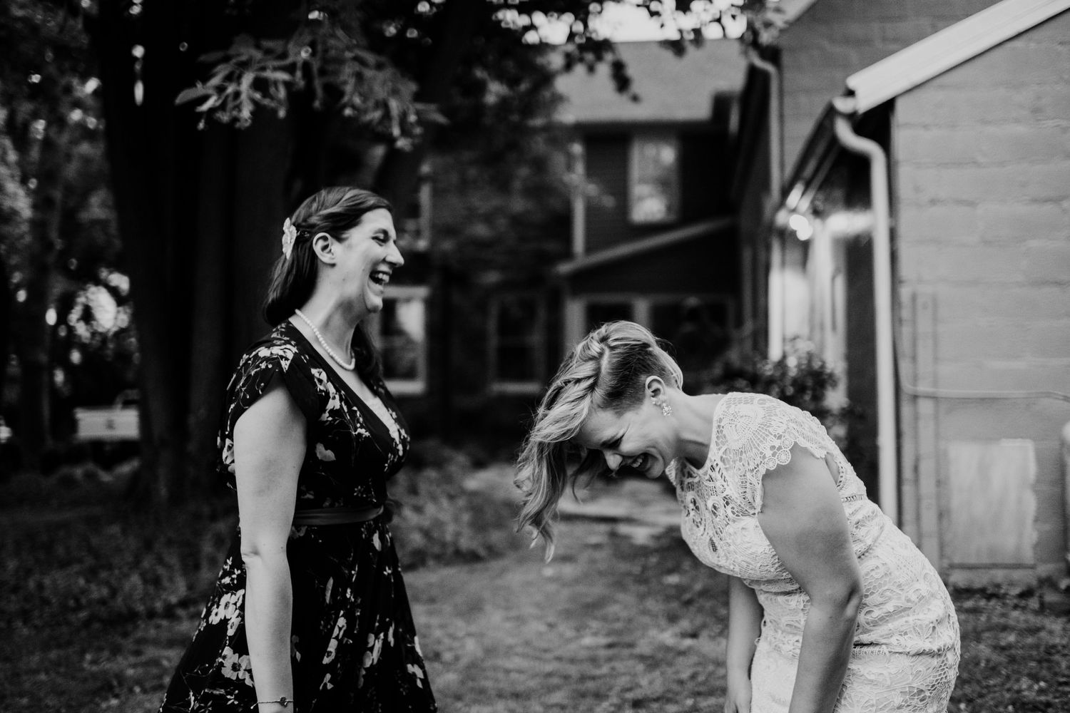 Two people share a lighthearted moment outdoors in front of a house.