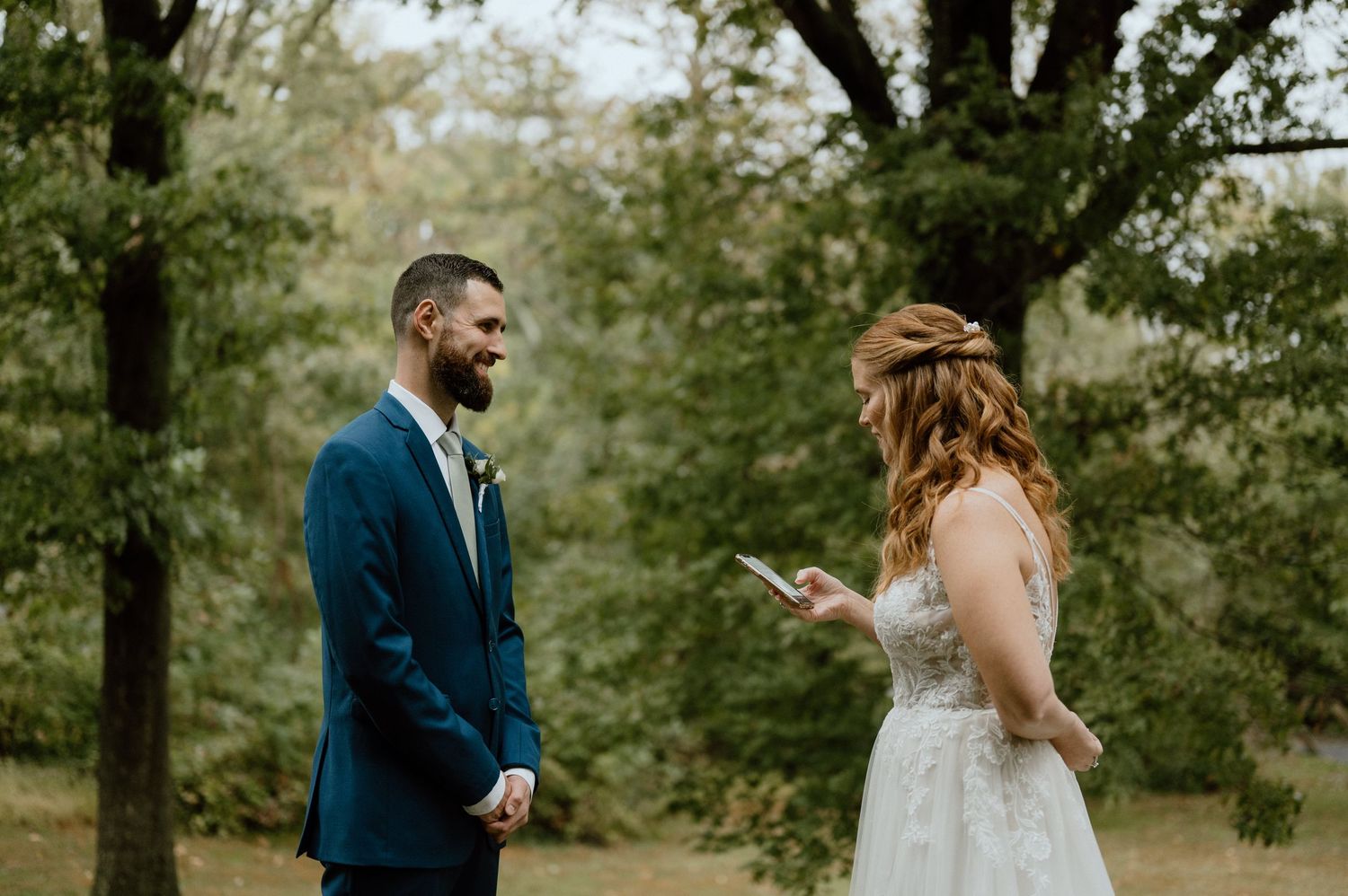 Wedding couple sharing a moment during their outdoor ceremony surrounded by trees.