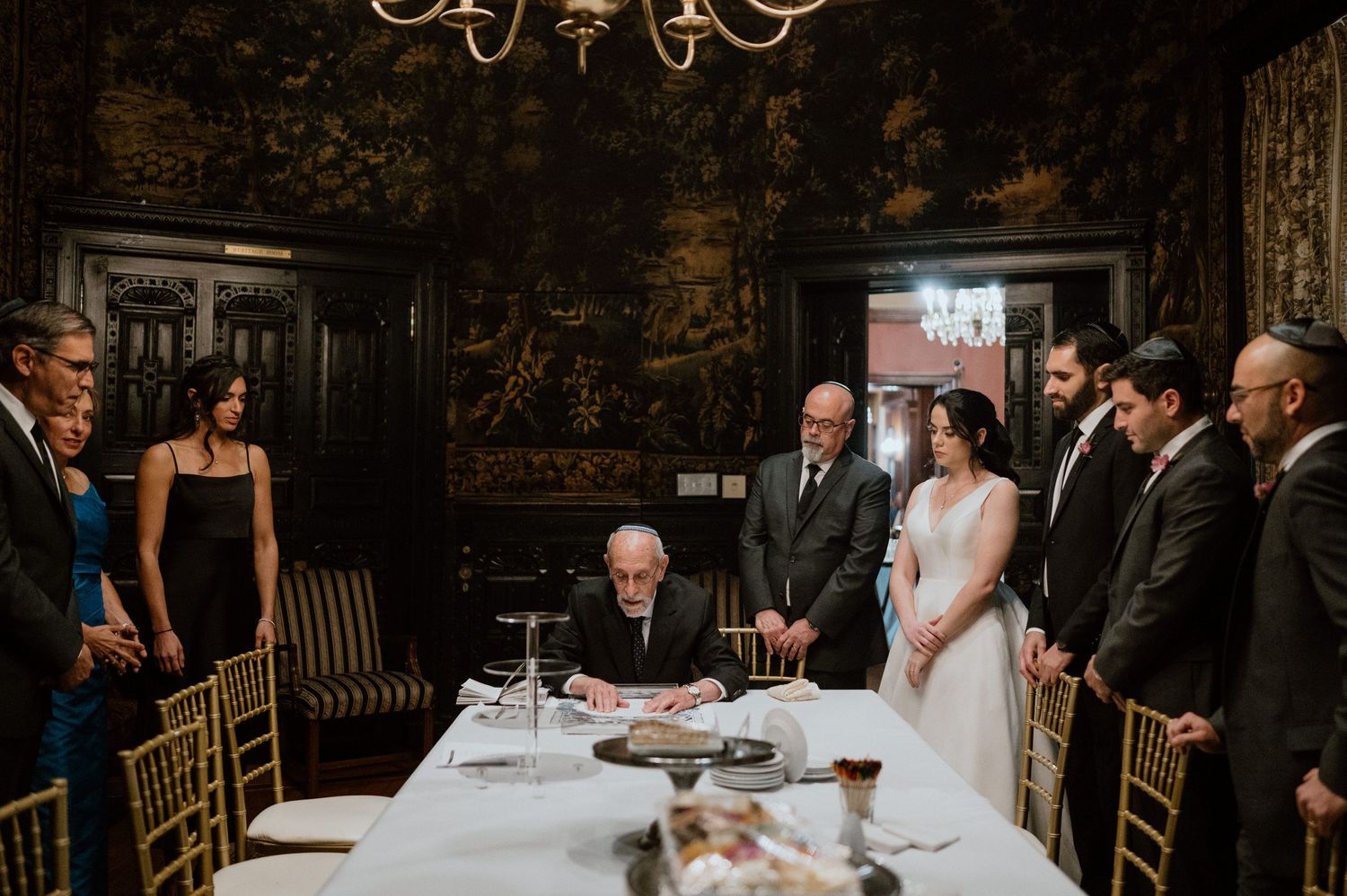 Wedding ceremony signing moment in an ornate dark wood paneled room.