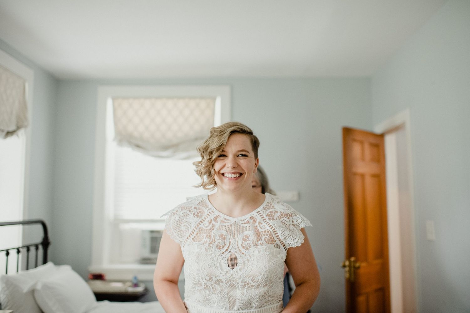 Wedding preparation scene in bright bedroom with natural window light.