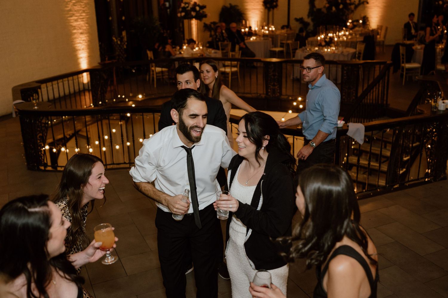 Guests dancing and celebrating at a dimly lit wedding reception venue.